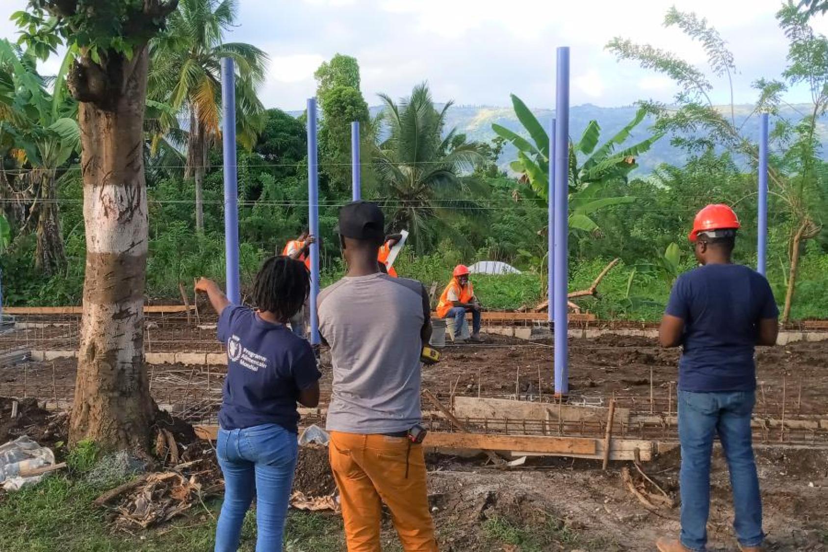 يتحدث موظف برنامج الأغذية العالمي مع أحد عمال البناء بينما يظهر الآخرون في الخلفية.