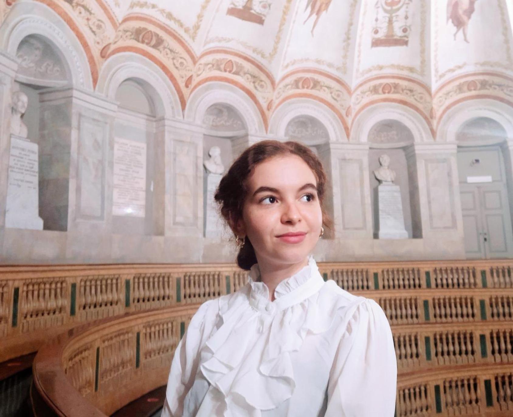 A woman in a white shirt looks off into the distance. 