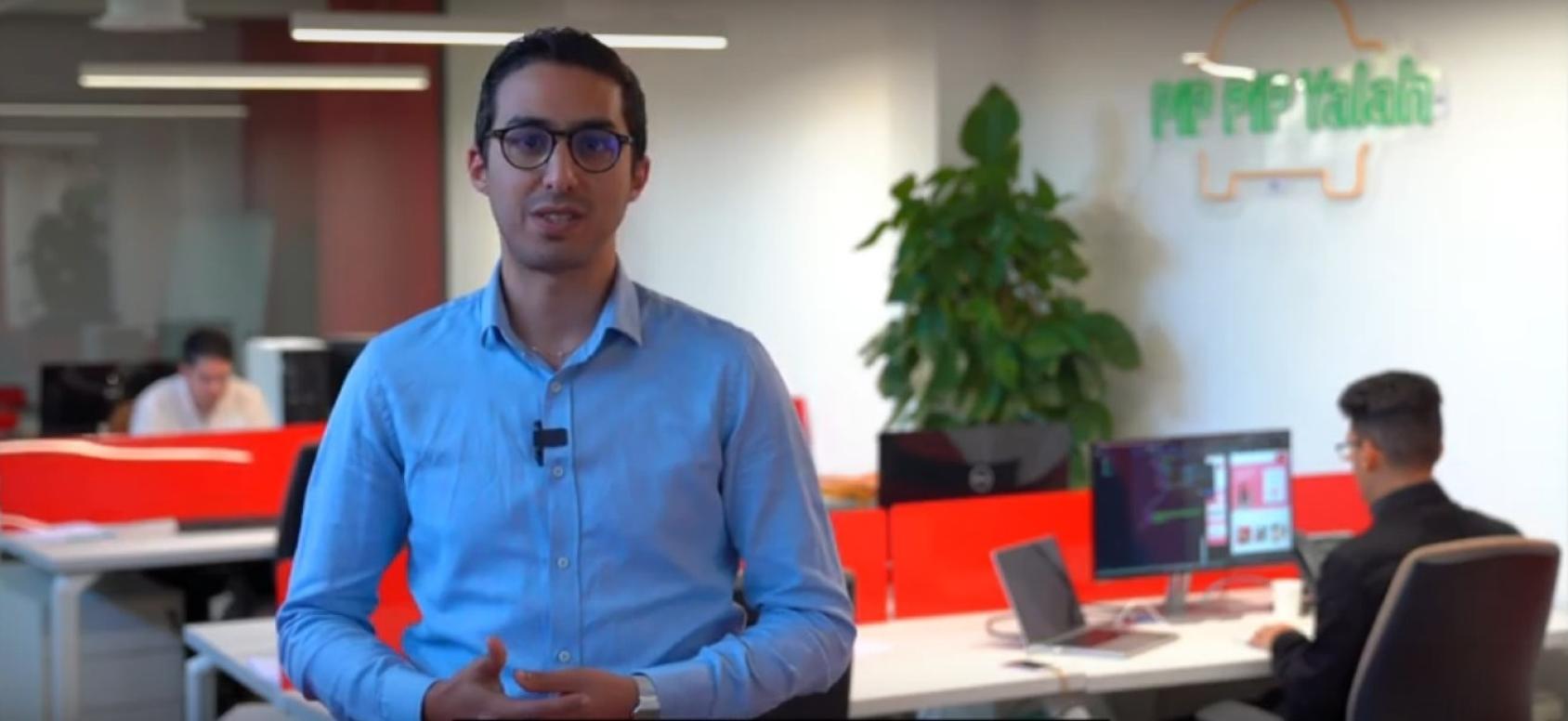 رجل يرتدي قميصًا أزرق ونظارة سوداء ينظر مباشرة إلى الكاميرا.