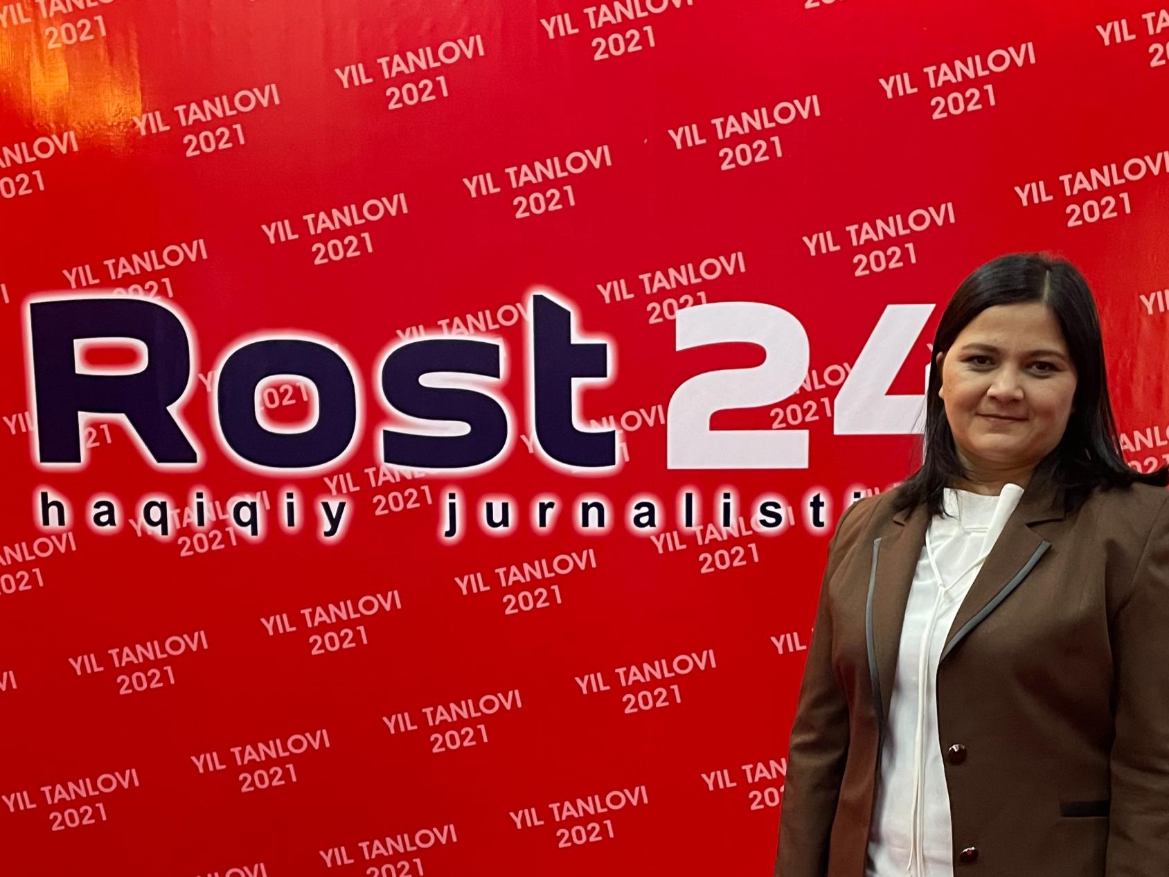  Молодая женщина в костюме позирует на фоне баннера с названием радиостанции