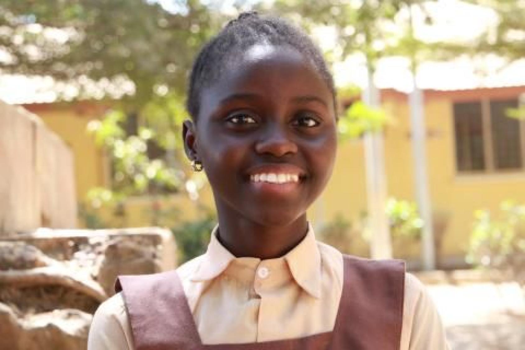 فتاة في زيها المدرسي تبتسم للكاميرا.