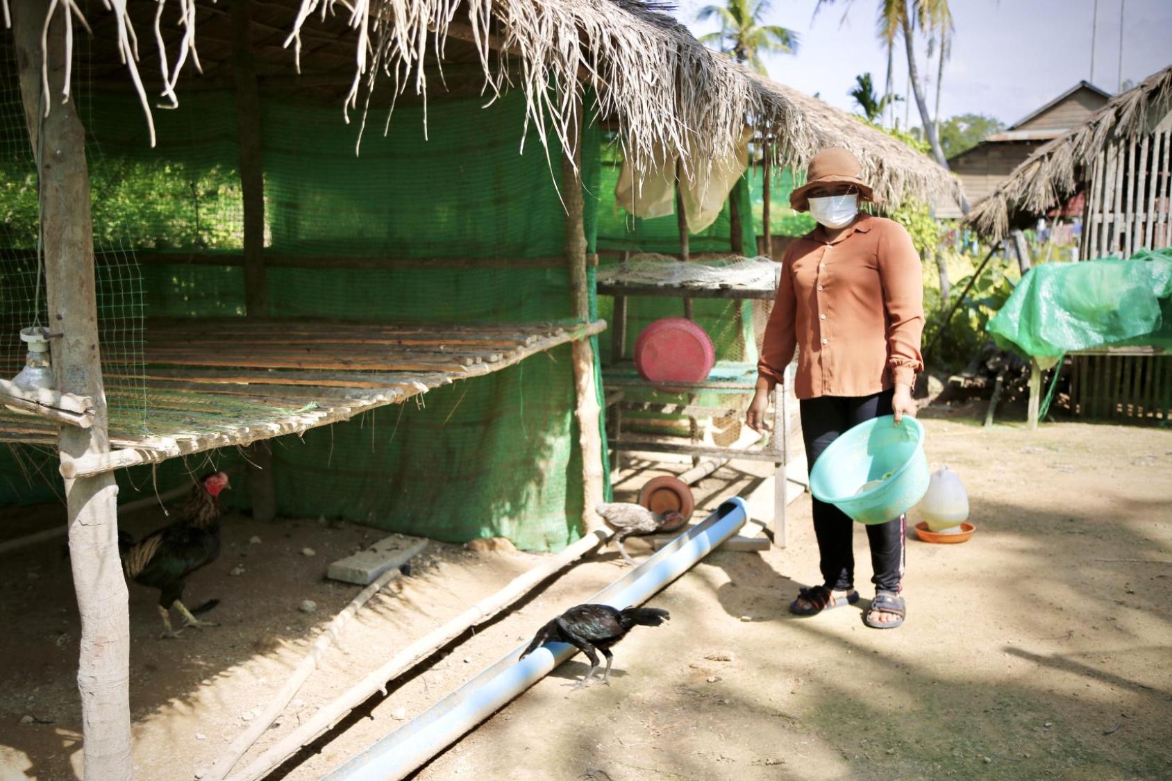 一个女人在喂鸡。