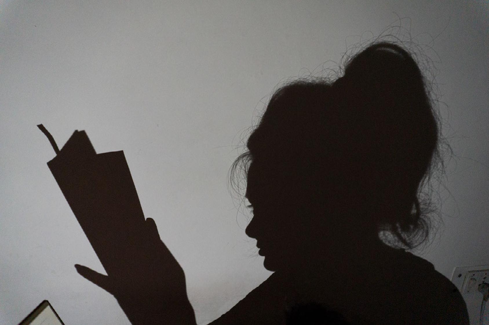 Силуэт женщины, которая читает книгу.