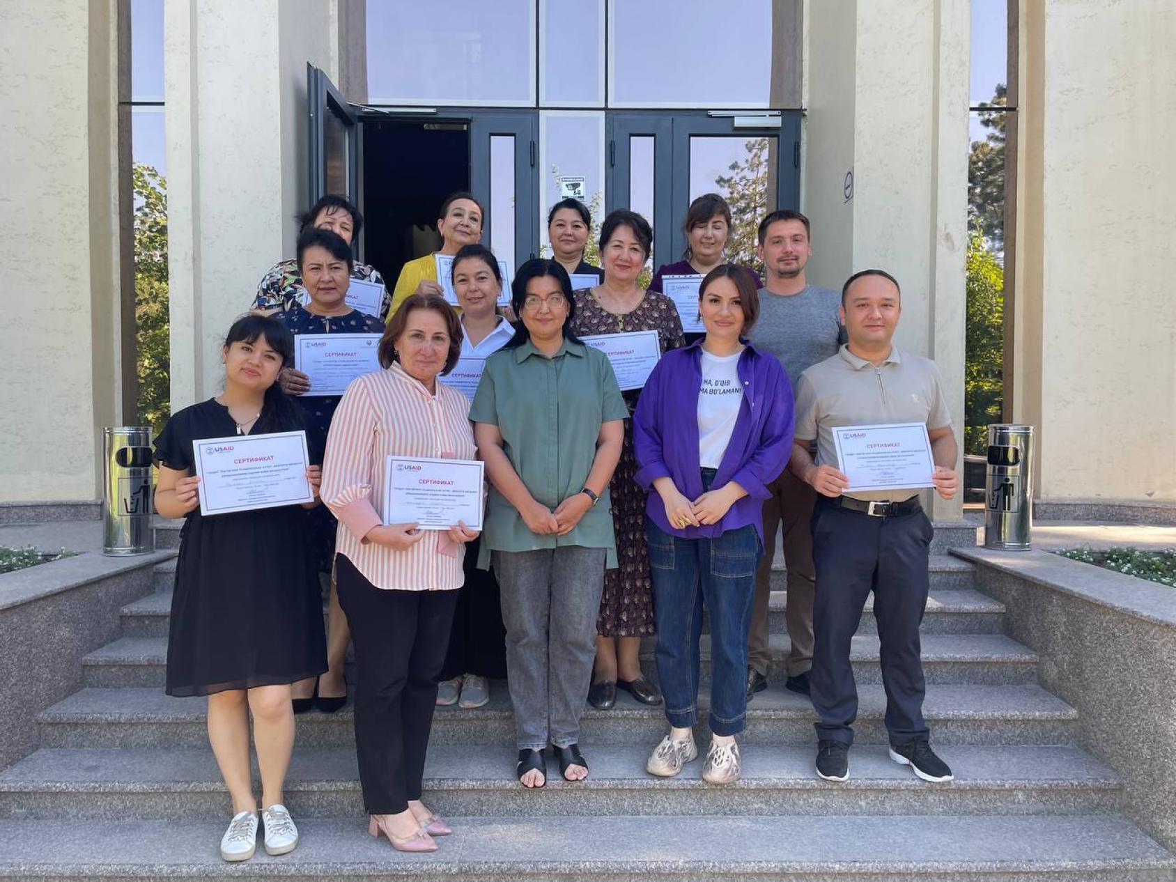 مجموعة من الأشخاص يحملون شهادات في أيديهم يقفون على شرفة المبنى.