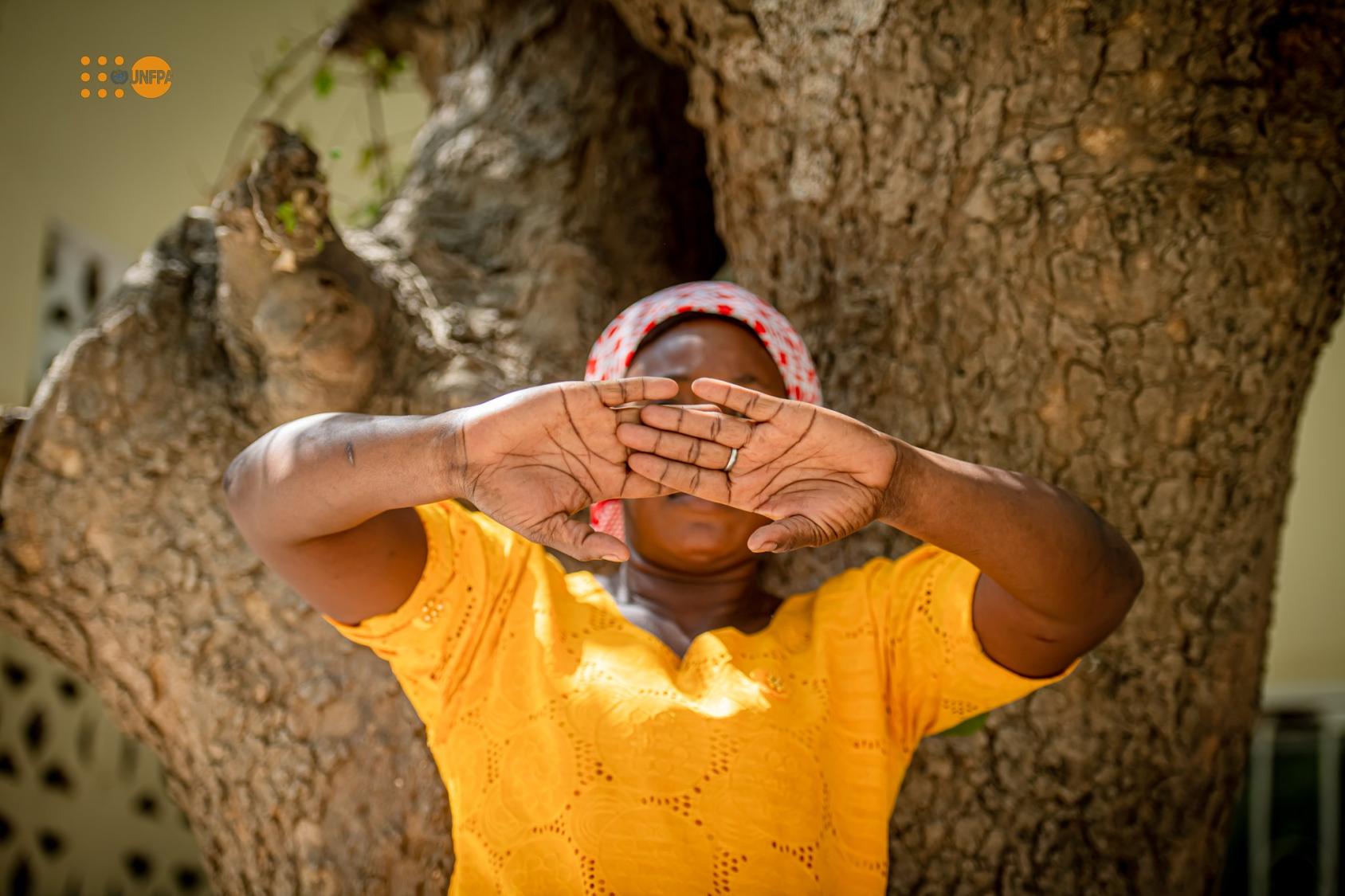 Jeune femme en robe jaune avec son visage couvert