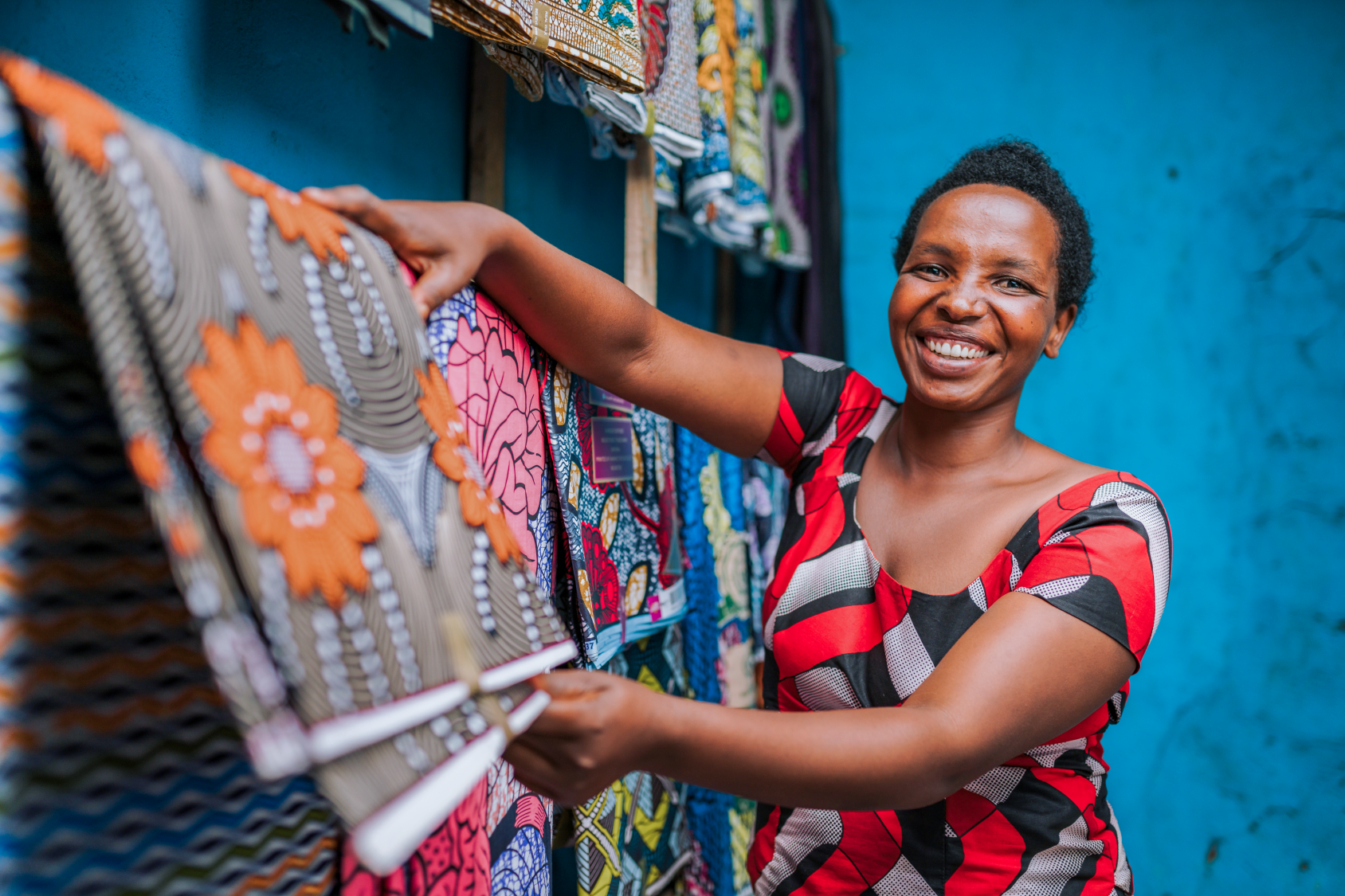 Woman in red and black dress hanging a colourful piece of cloth on a line.