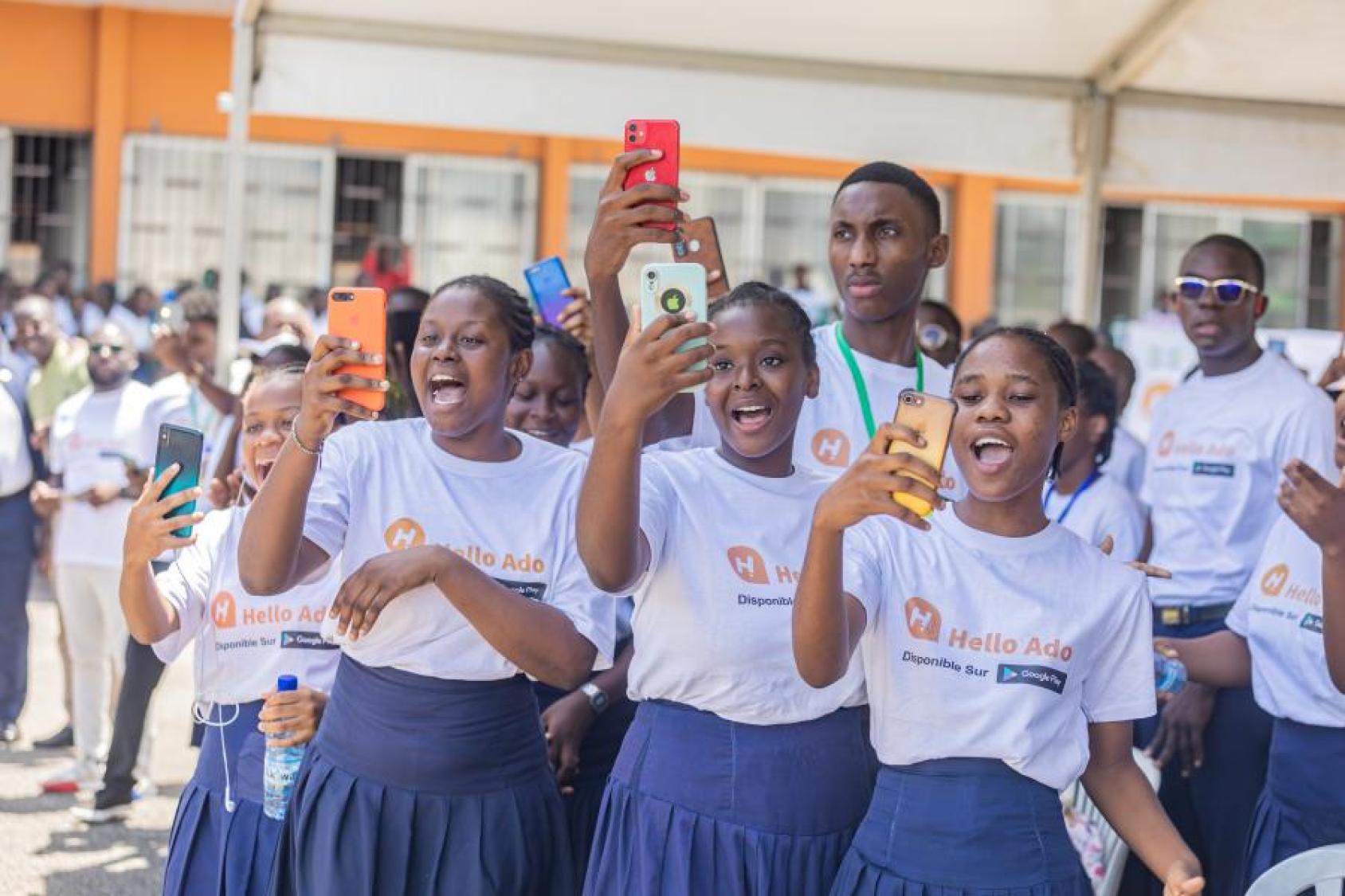 Jeunes en uniforme scolaire bleu avec un téléphone portable à la main