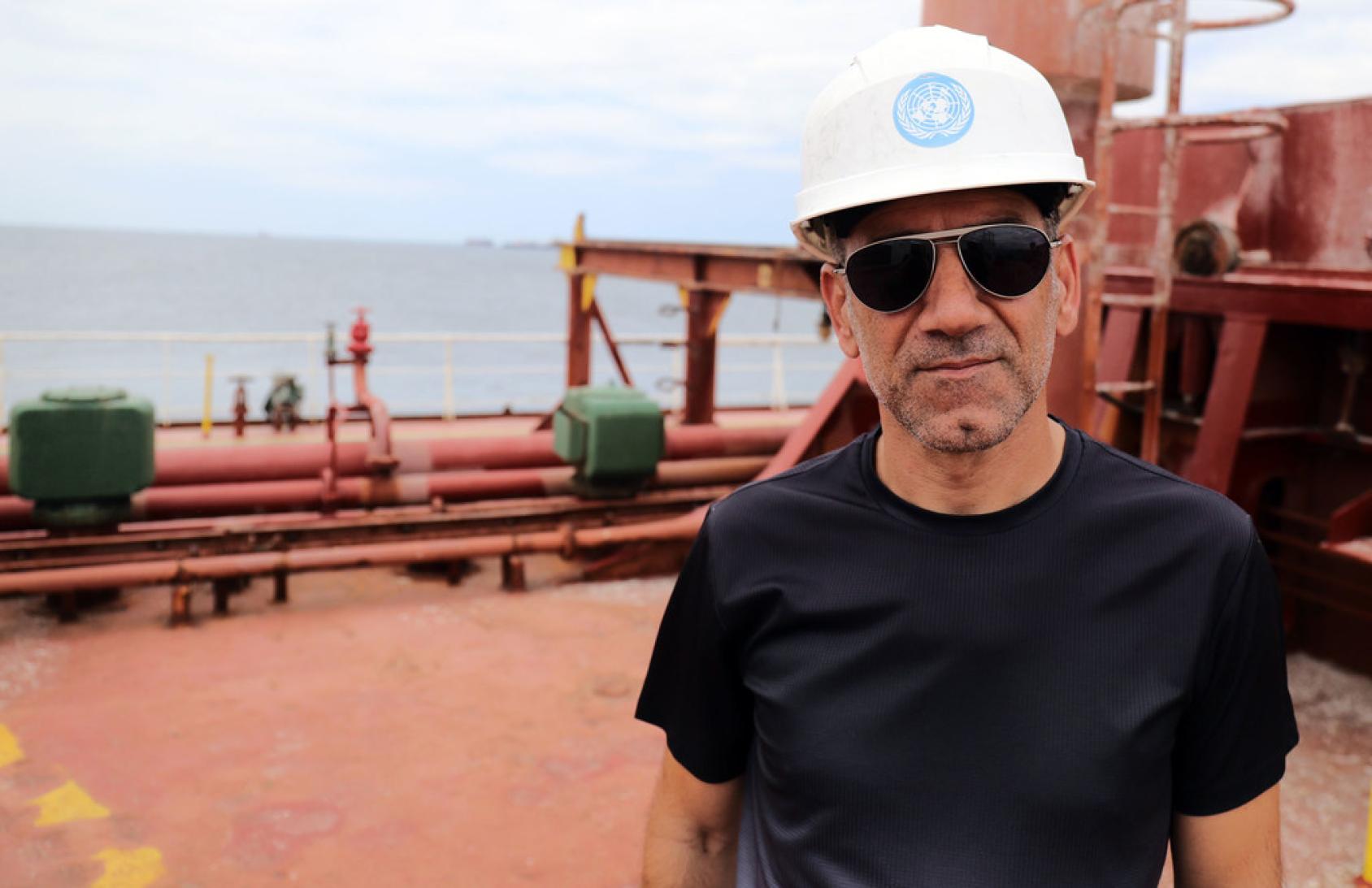 An inspector in a hard hat, on a ship.