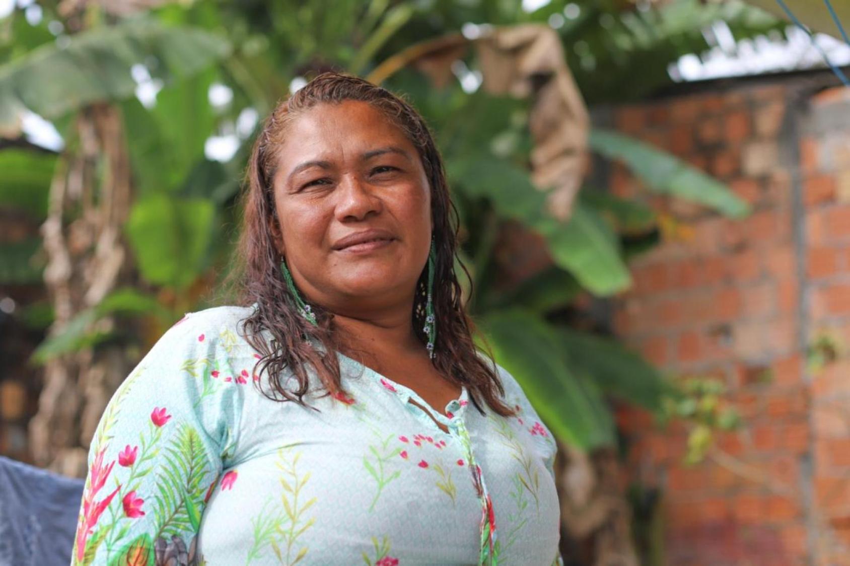 A woman in a green dress stands in front of a banana tree