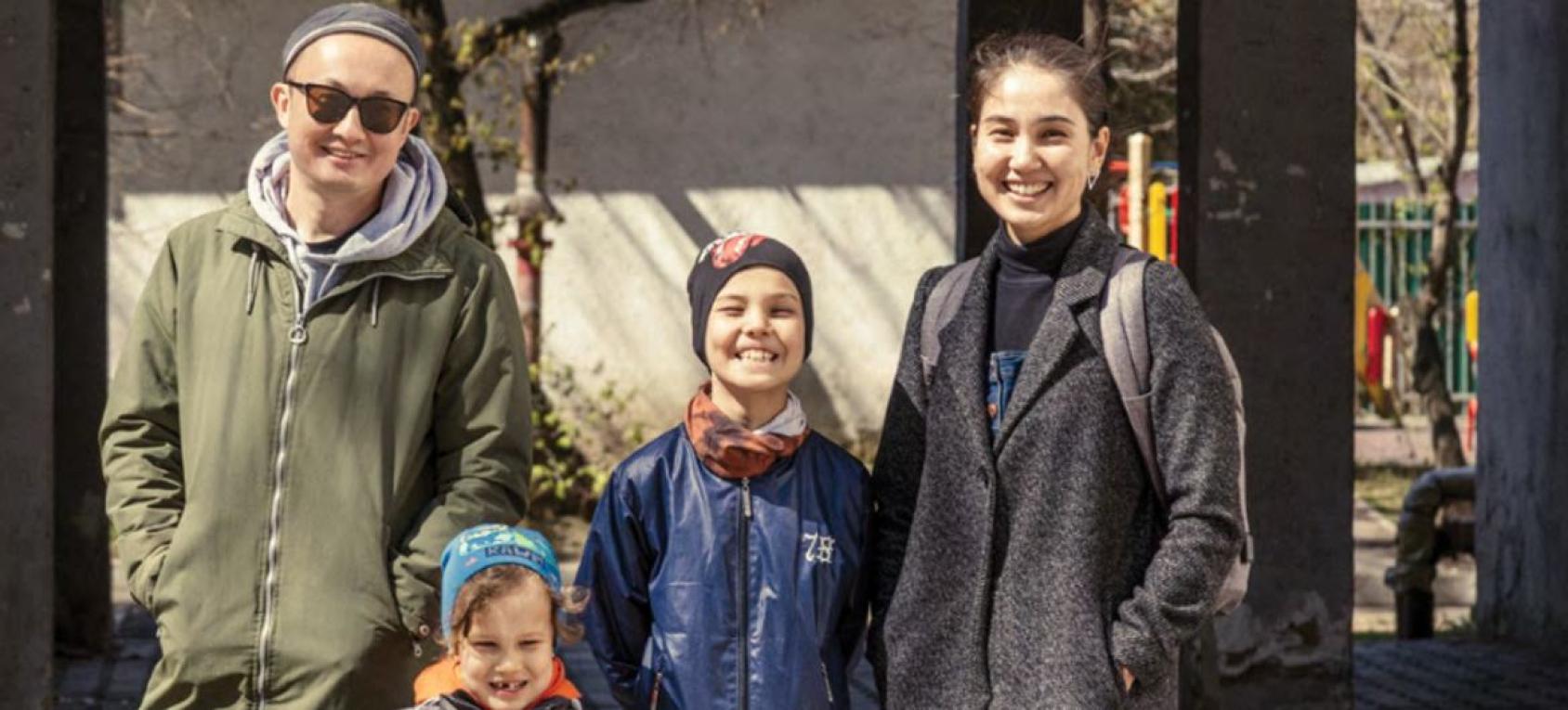 Молодая пара с двумя детьми на улице в солнечный день