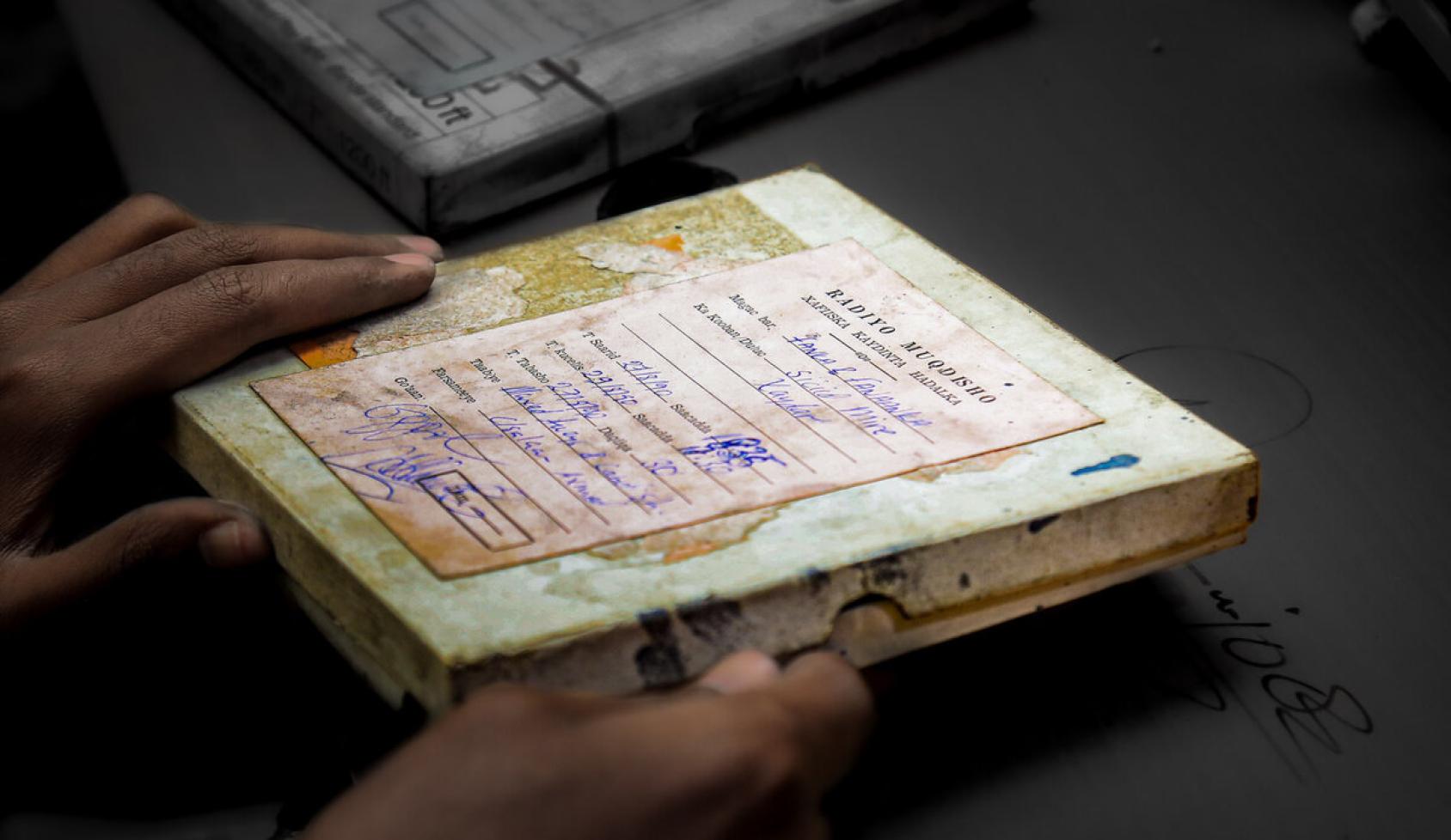 A shot of two hands holding an audio cassette with scribbles on the cover