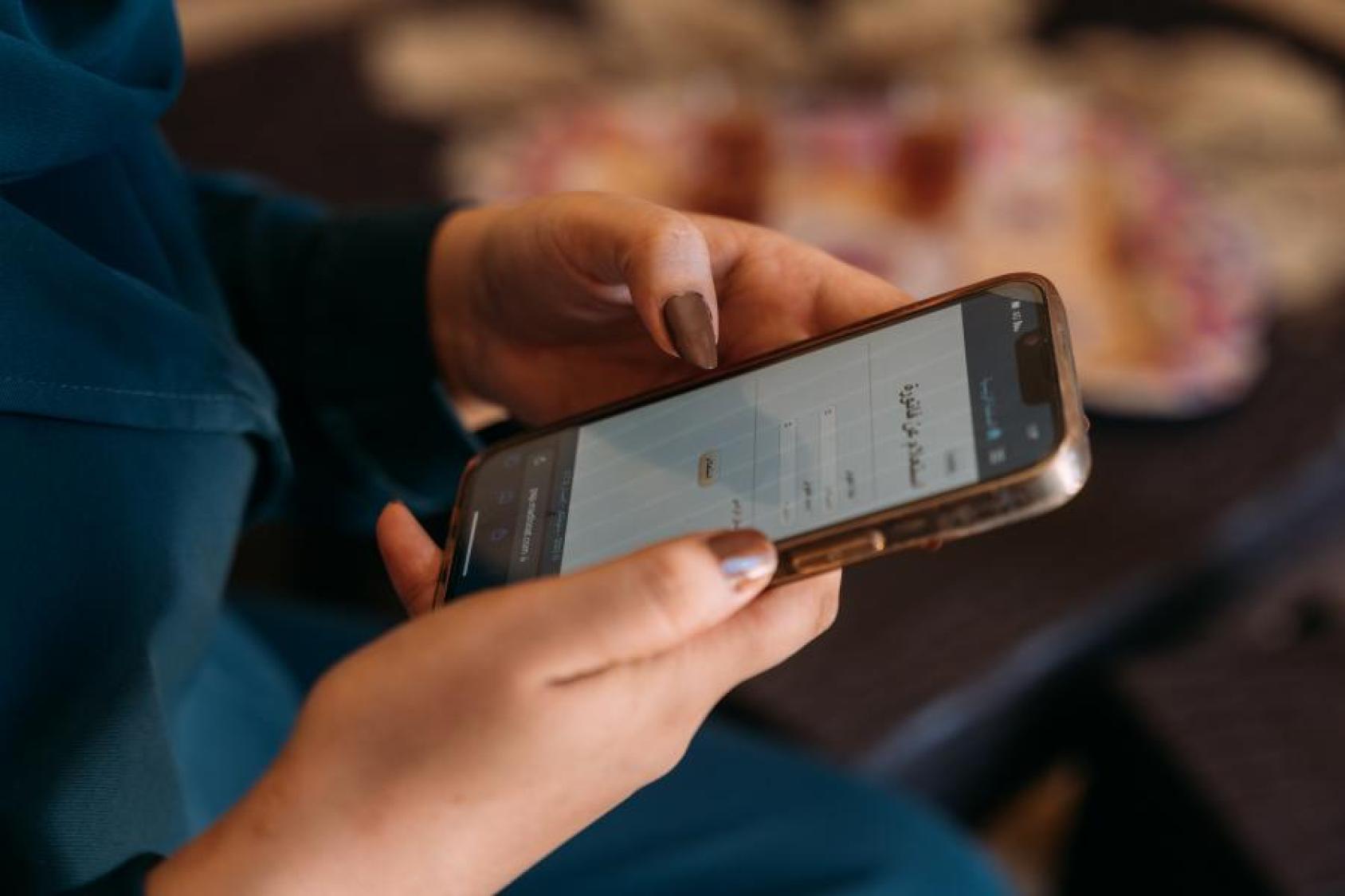 A woman's hands holding a smart phone and scrolling through.