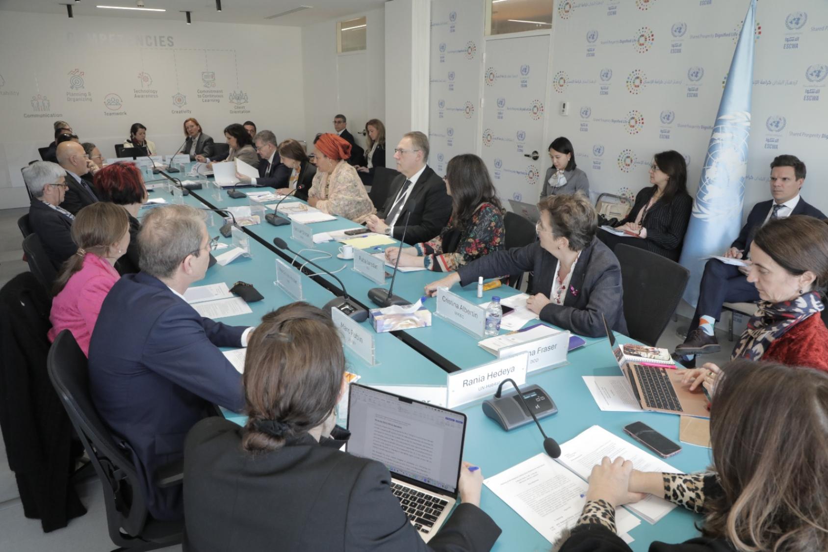A long table with several people in black and grey suits sitting around it