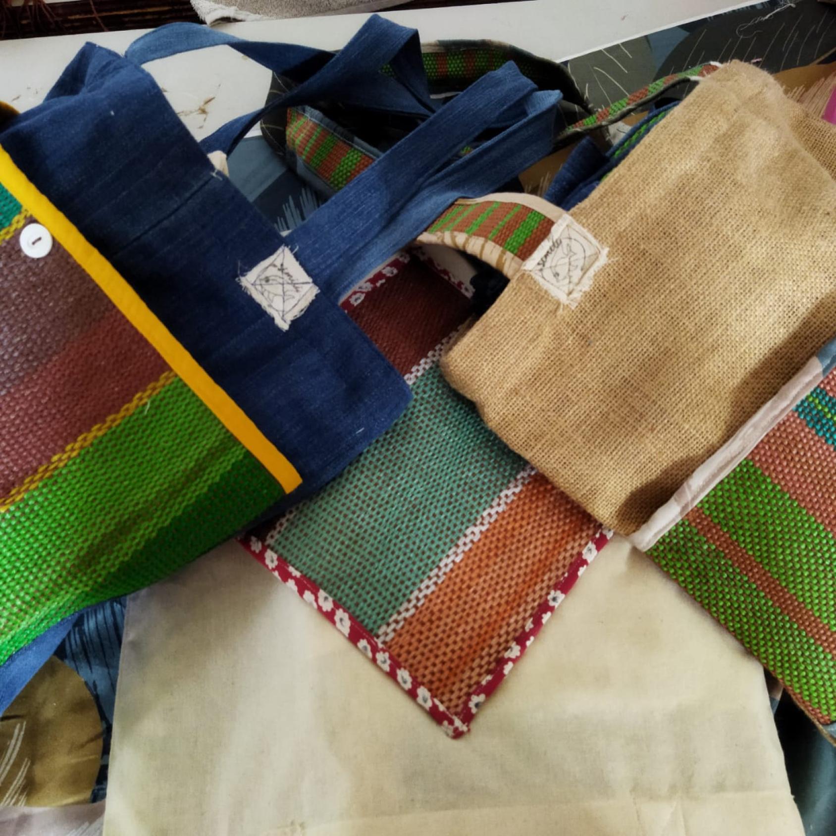 Three bags one laying on top on another, in various colours and made of jute style material