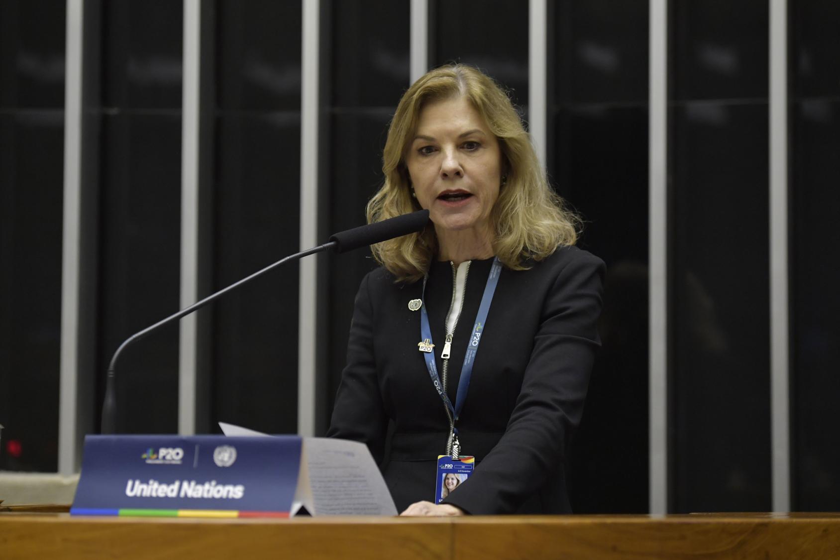 The RC in Brazil, Silvia Rucks, in a black suit speaks into a microphone at the G20
