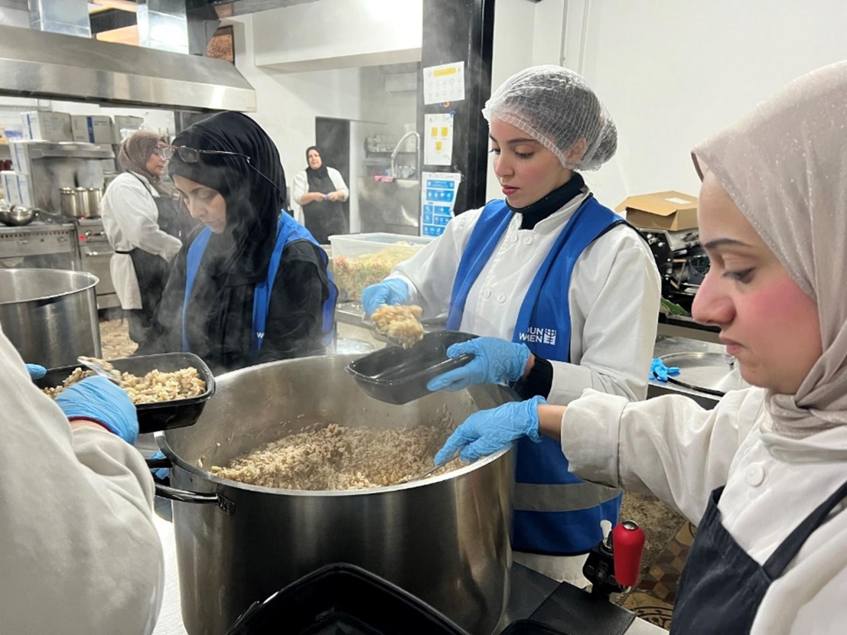 A woman in a white dress and blue apron mixes ingredients in a giant vessel