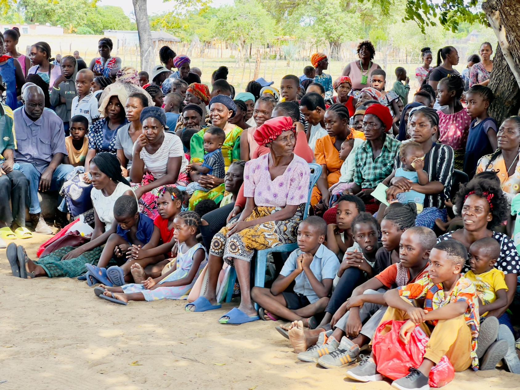 A gathering of women and children in colourful clothes, as they wait to receive provisions