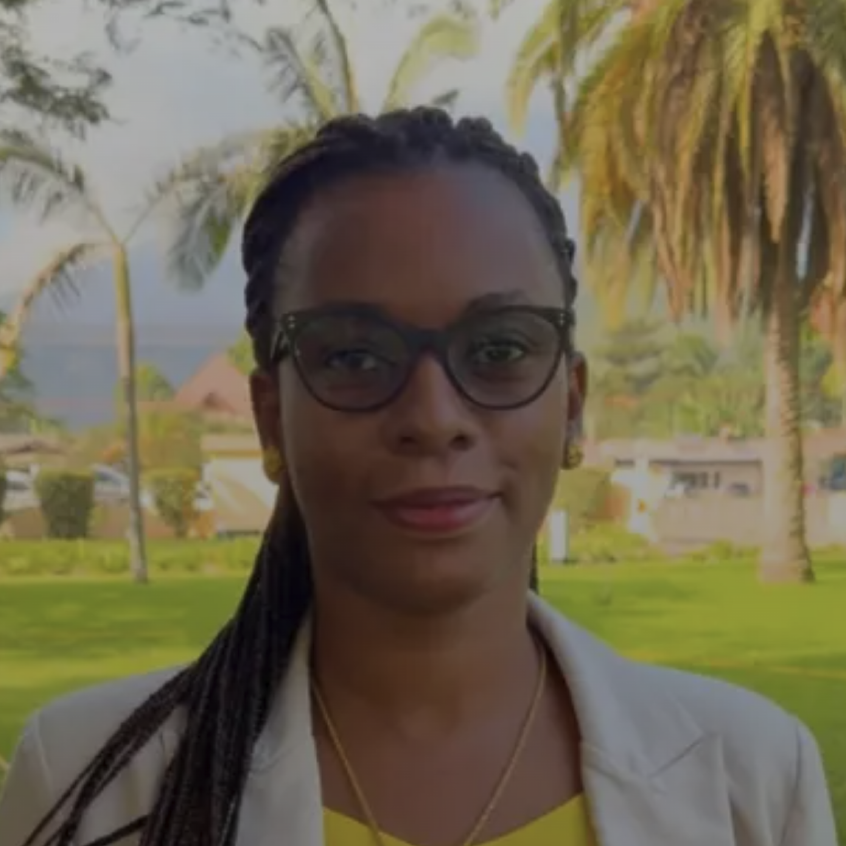 A woman stands in front of some trees.