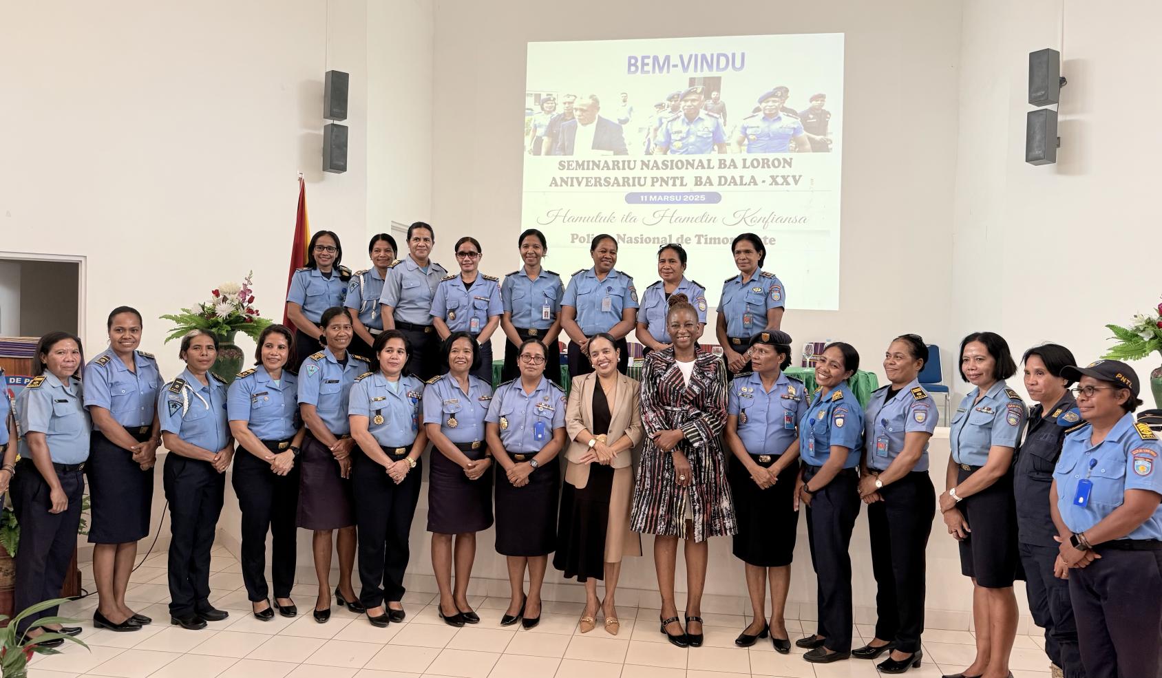 Two rows of women police officers in blue uniforms standing with another women in a darker dress.