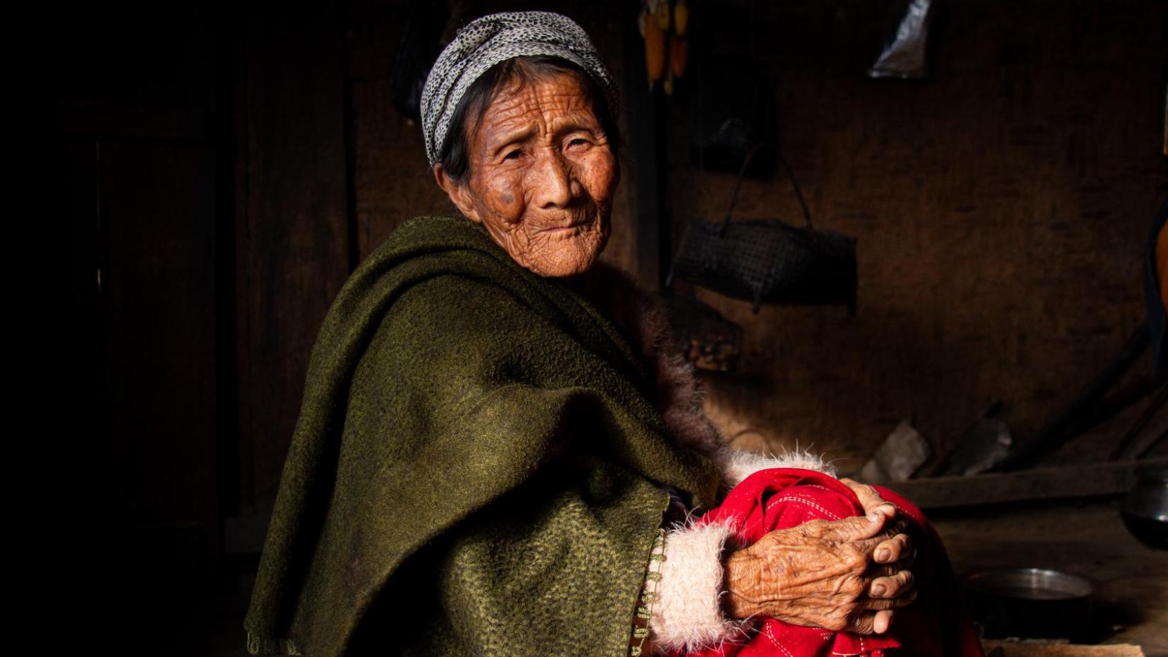 An elderly woman sitting on the floor