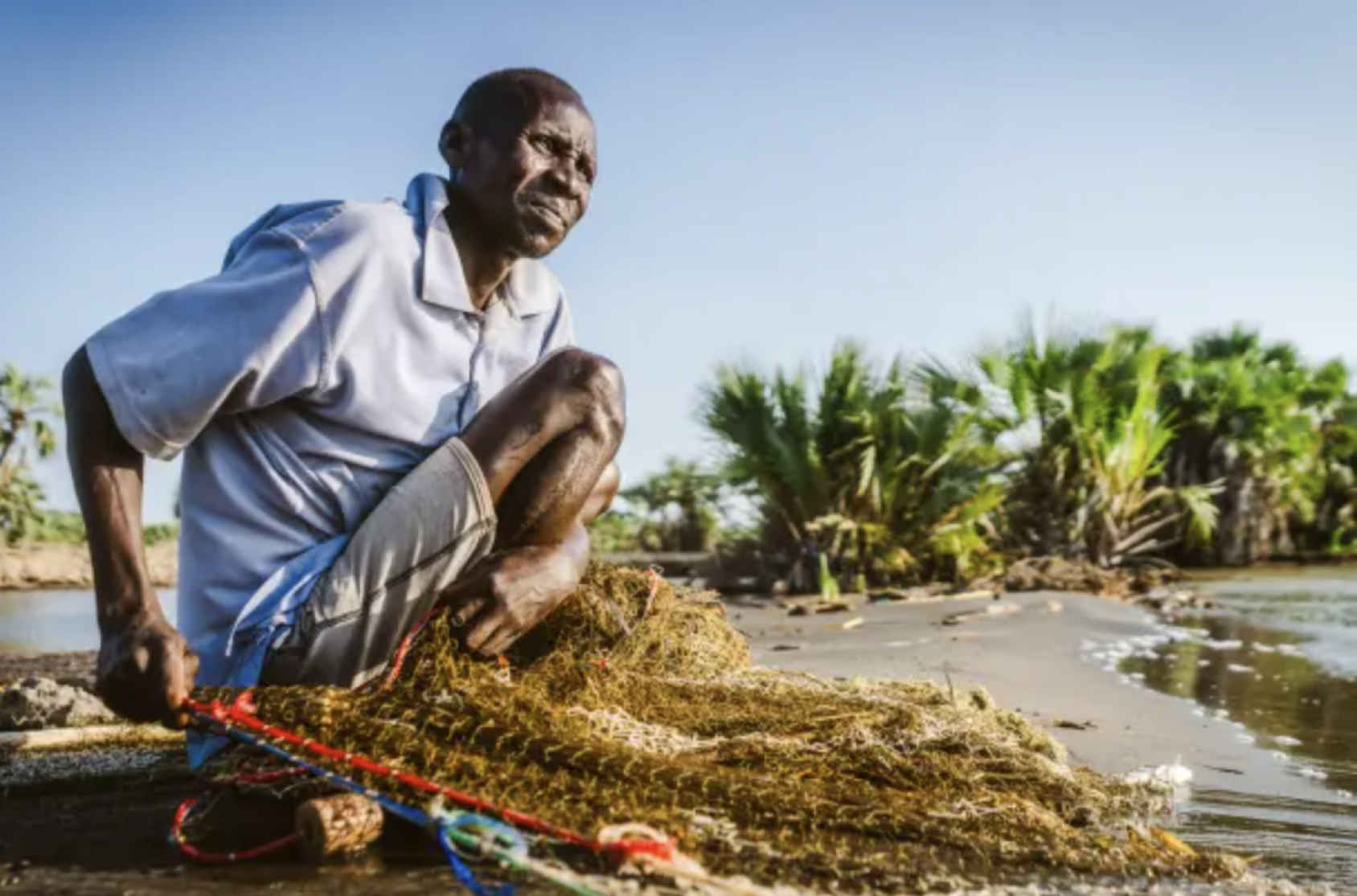 一位非洲男性坐在地上准备捕鱼