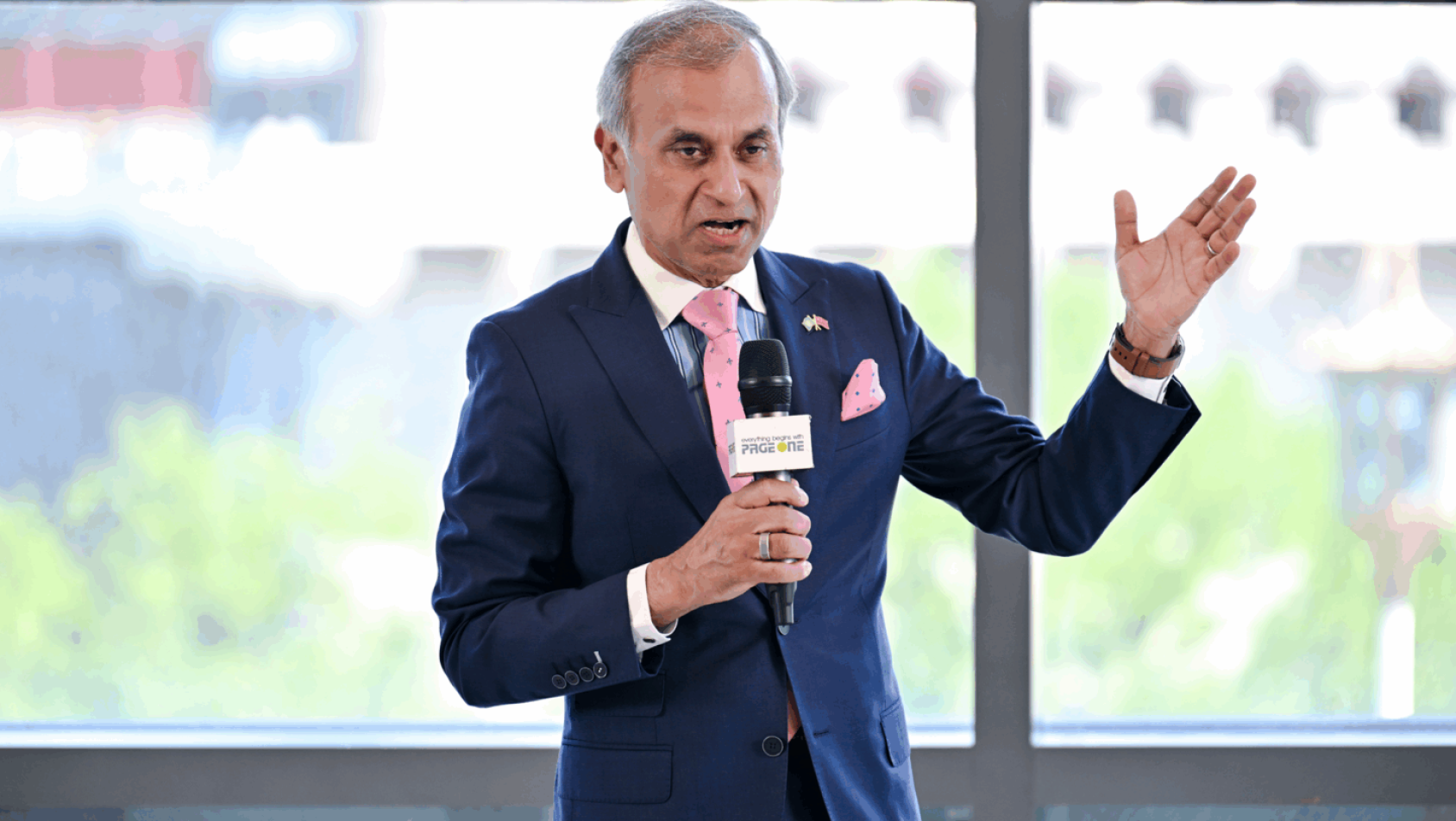 一位身着西装的男士拿着话筒站着发言