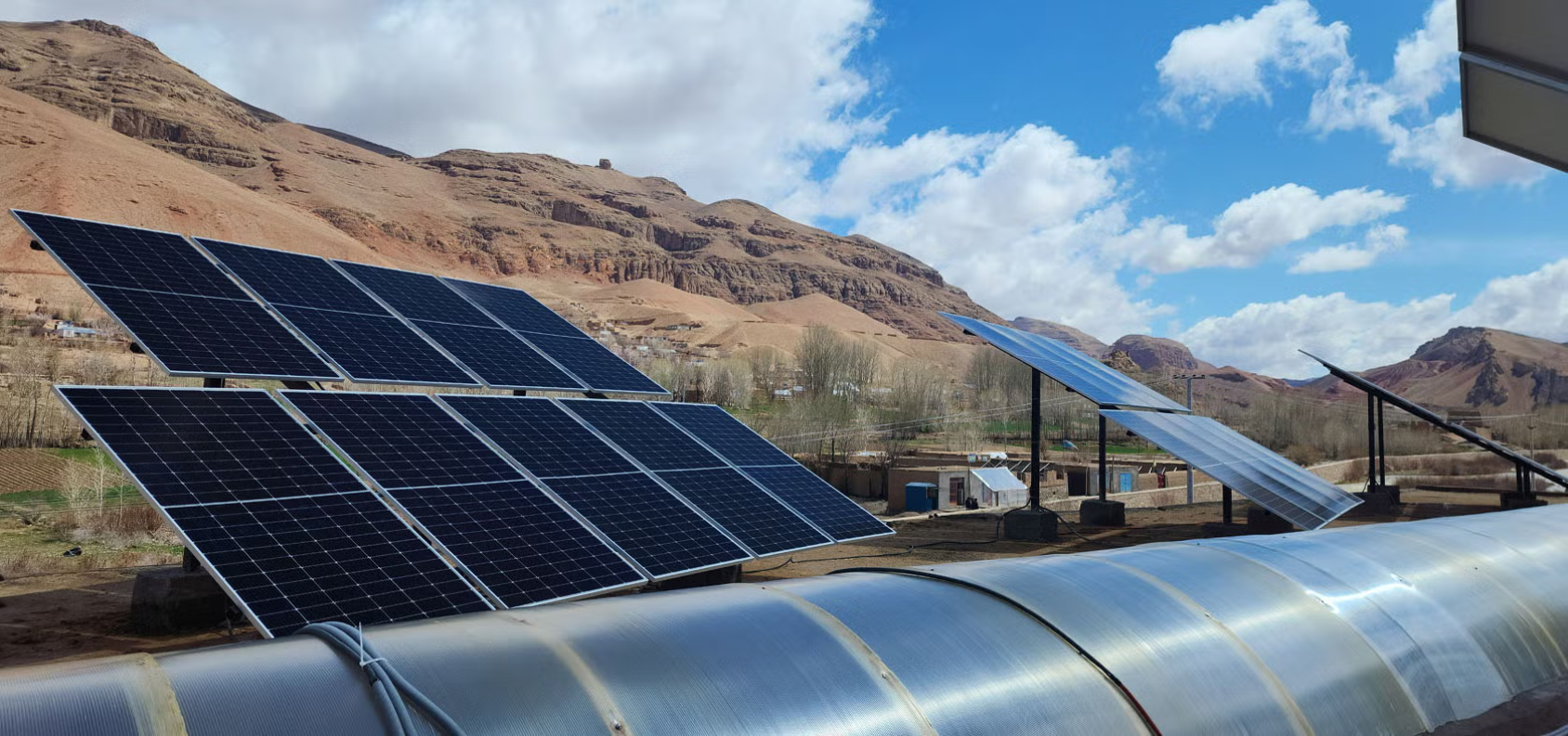 Grey solar panels in front of a mountainous background