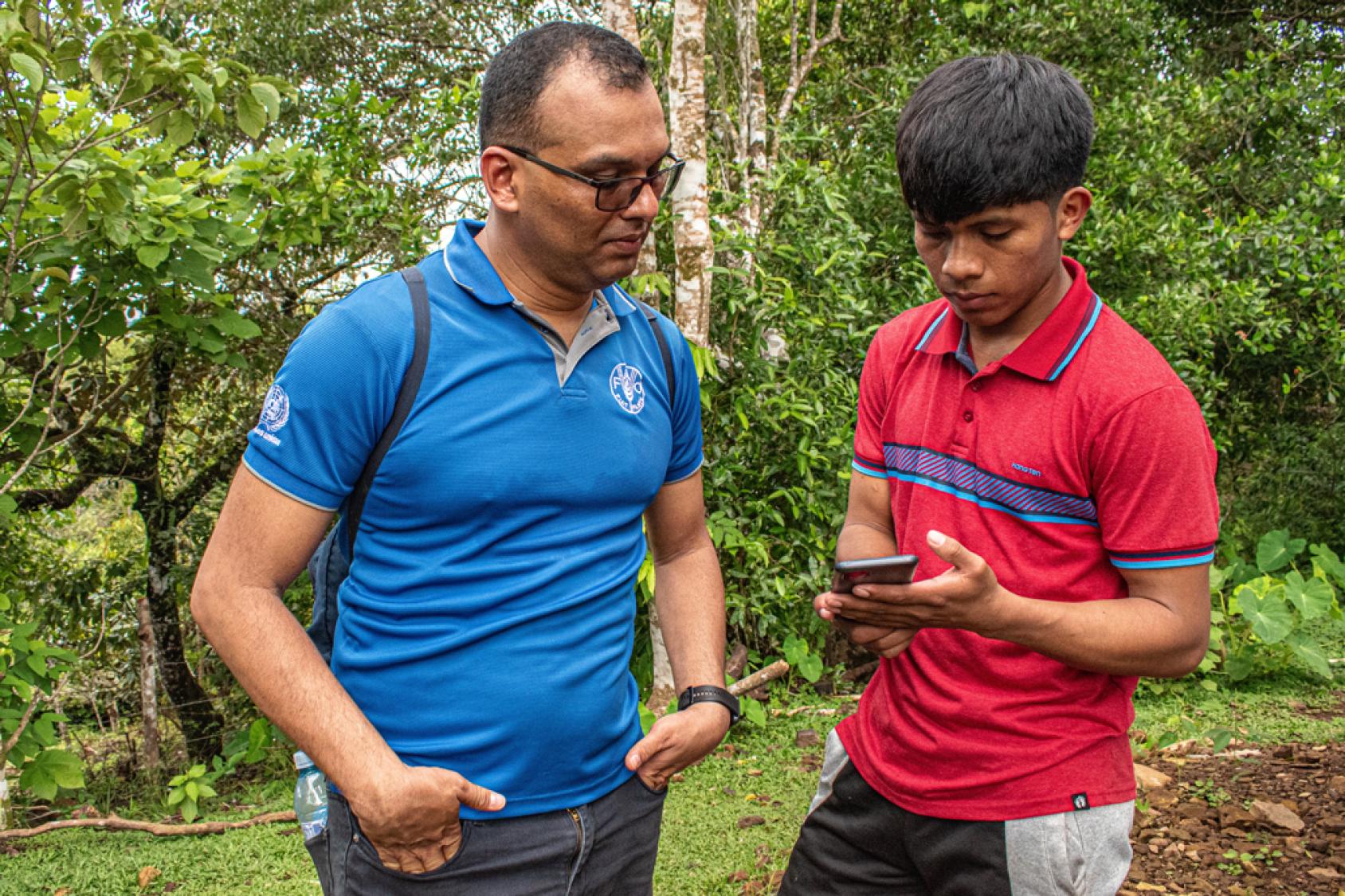 Двое мужчин смотрят на мобильный телефон.