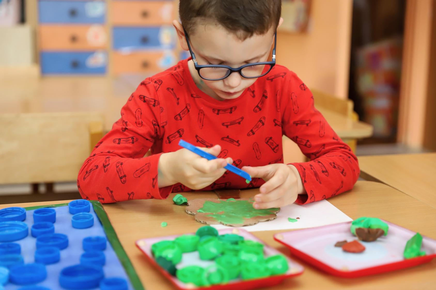 Маленький мальчик делает поделку из пластилина
