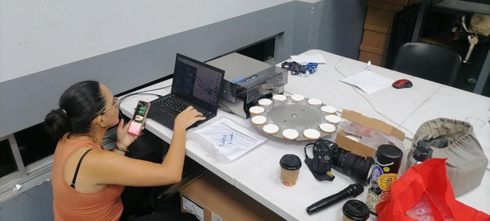 A woman working on a 3d printer in a room.