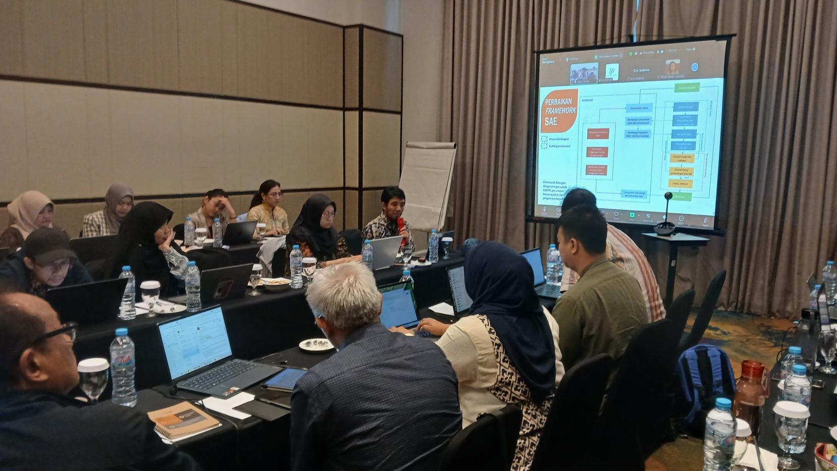 A group of people in a conference room discussing a presentation displayed on a large screen