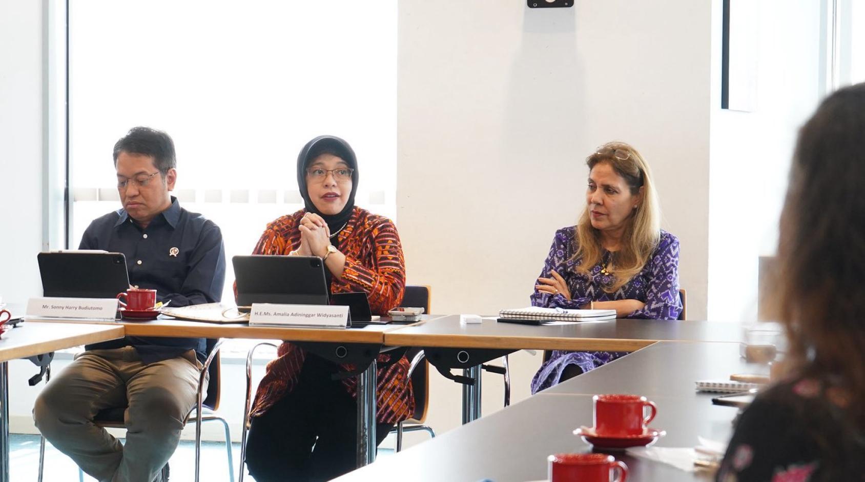 A group of people in a conference room speaking to each other