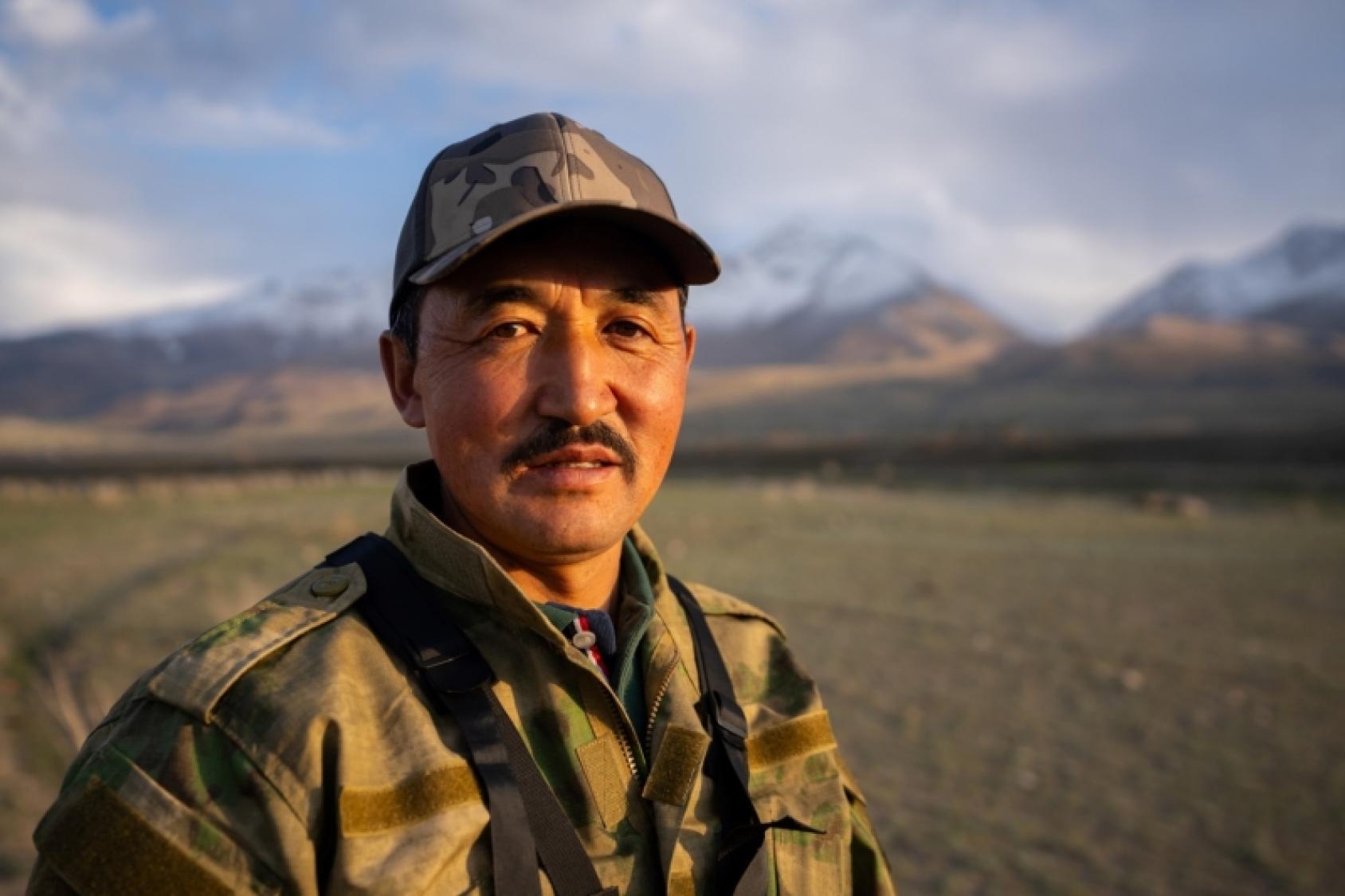 Мужчина крупным планом смотрит в камеру на фоне гор