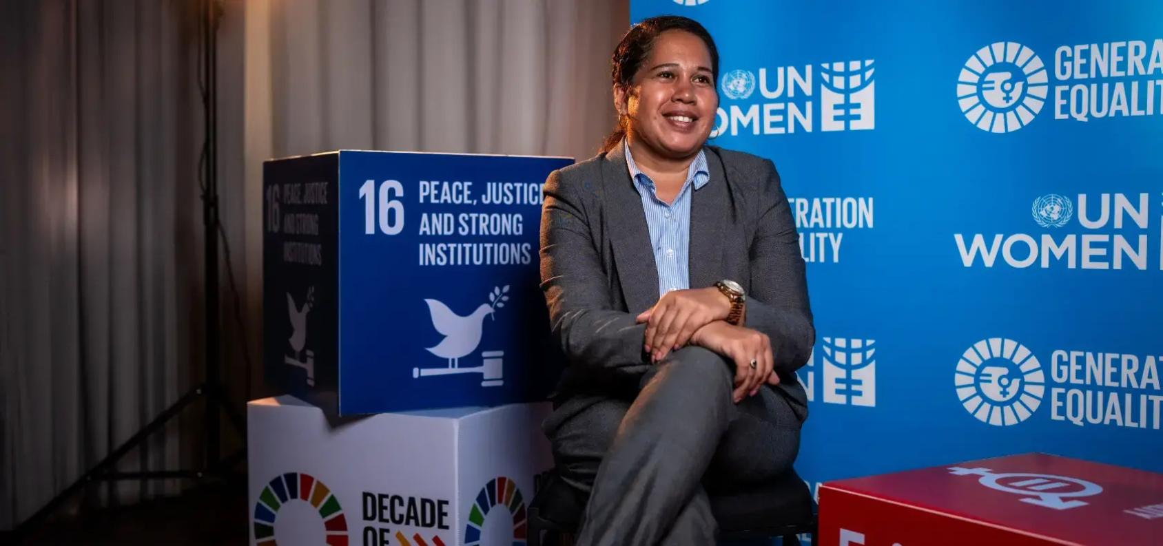 A Timorese woman sits in front of cubes promoting the Sustainable Development Goals.