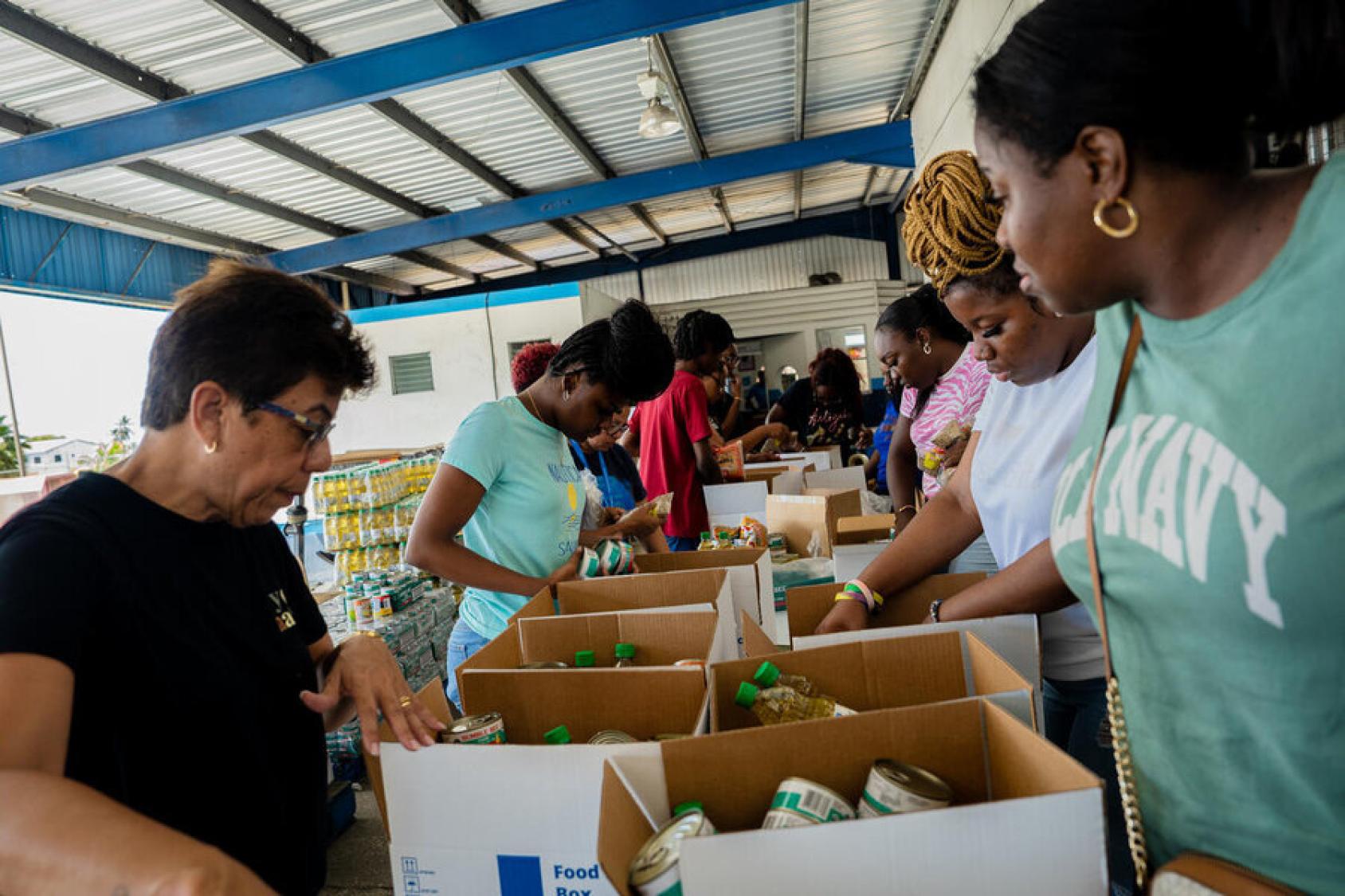 Women humanitarians prepare boxes of supplies after a hurricane made landfall in Jamaica.