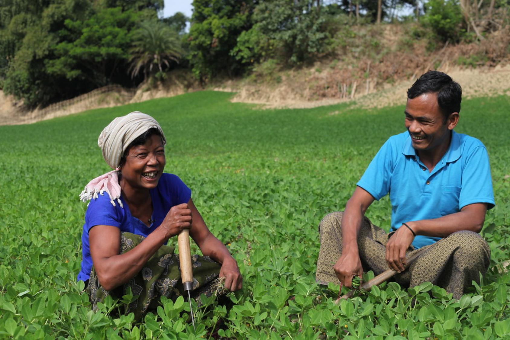 A man and woman sit in a field in Bangladesh.