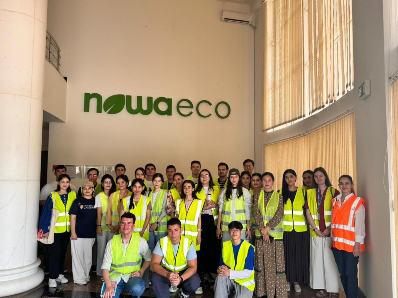 Команда молодых людей в жилетах делает совместное фото.