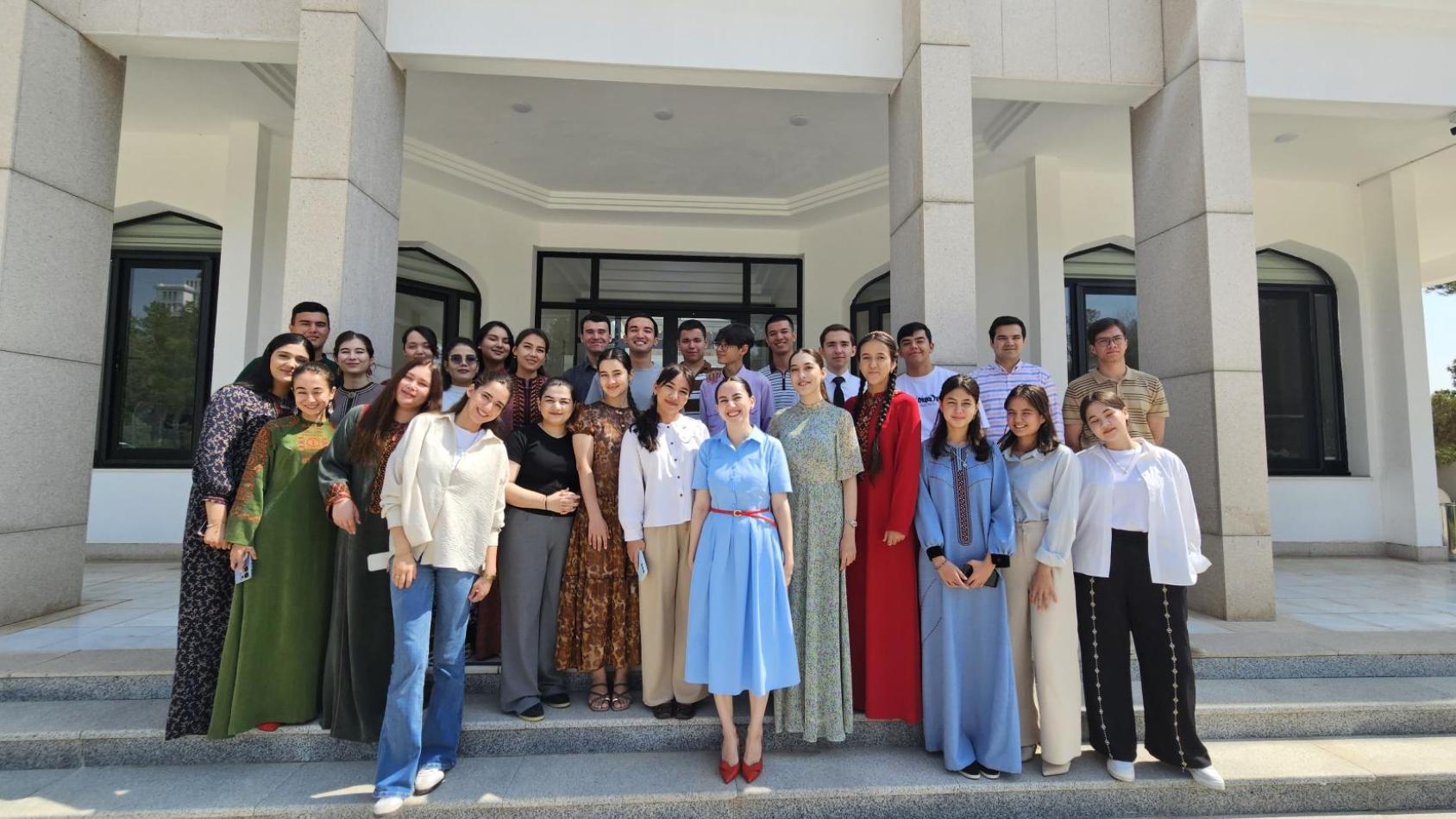 Совместное фото молодых людей в солнечный день у здания.