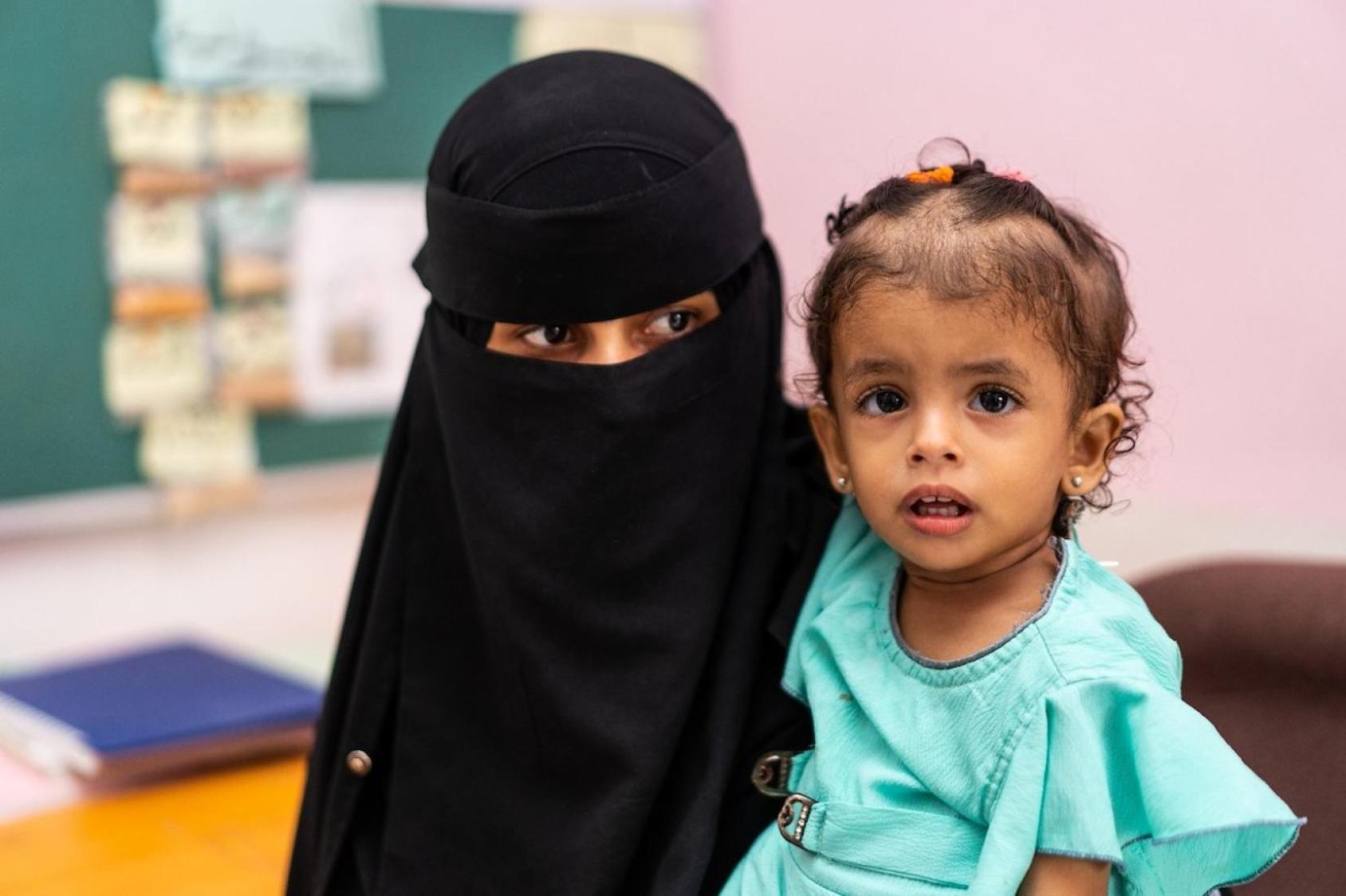 صورة لأم تصطحب إبنتها إلى مركز صحي تم تأهيله بدعم من مشروع " مشروع تعزيز المرونة المؤسسية والإقتصادية في اليمن SIERY"