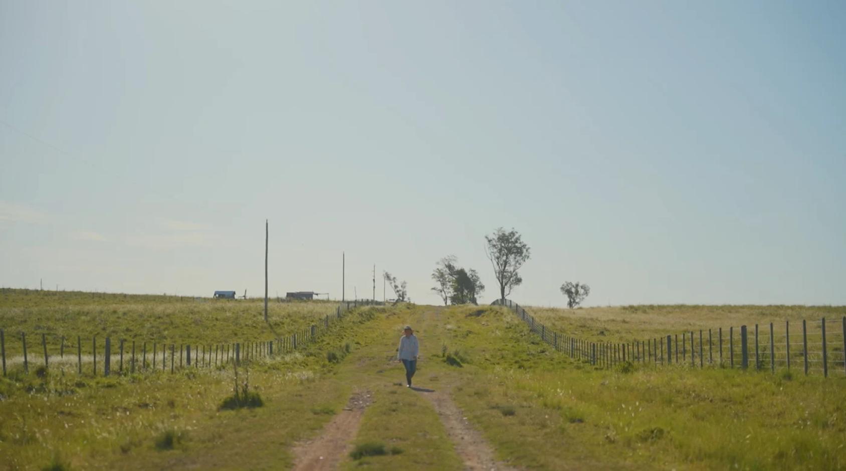 A large-shot view of a woman in a field. 