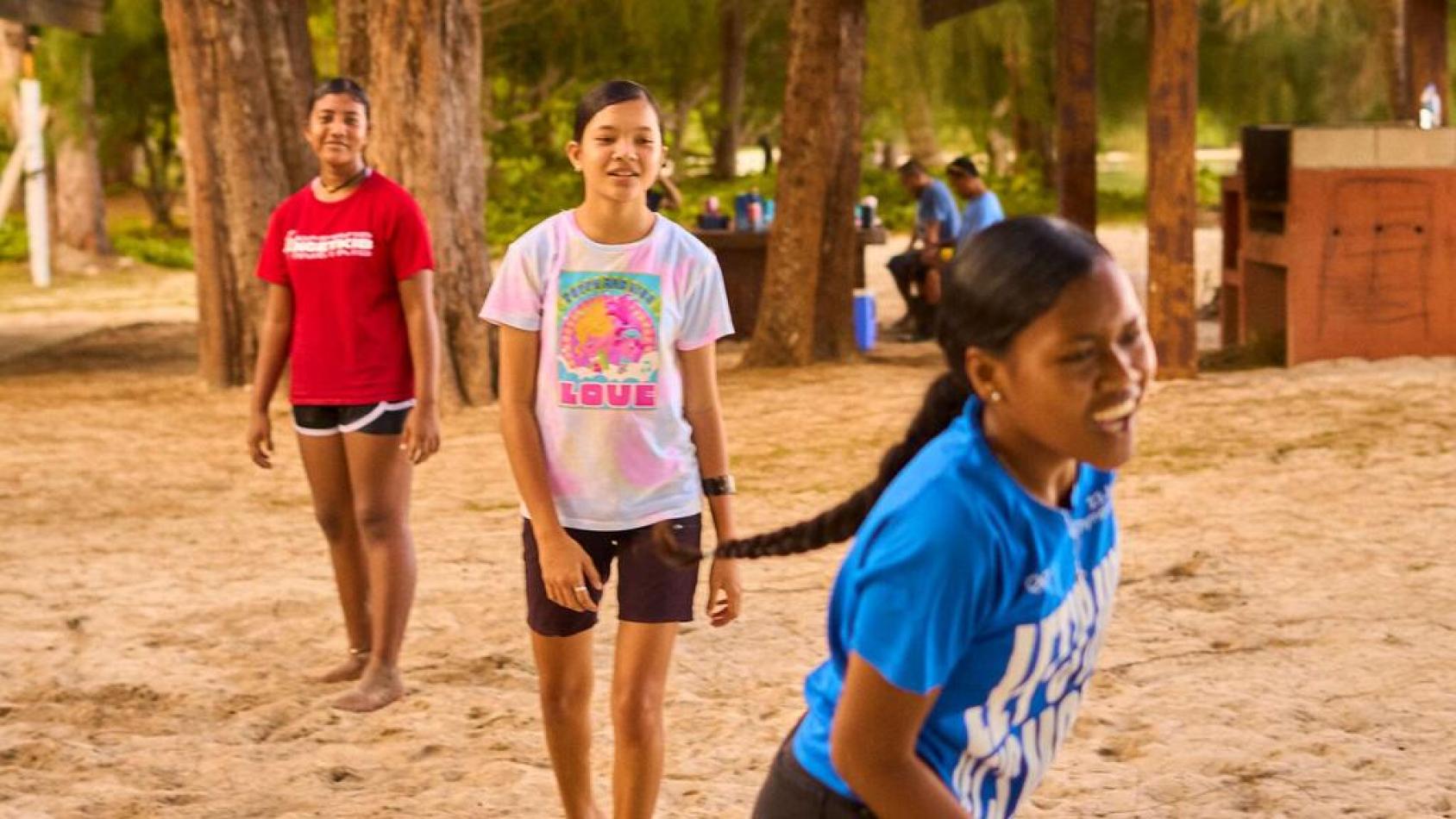 Three girls in Palau play on a beach.
