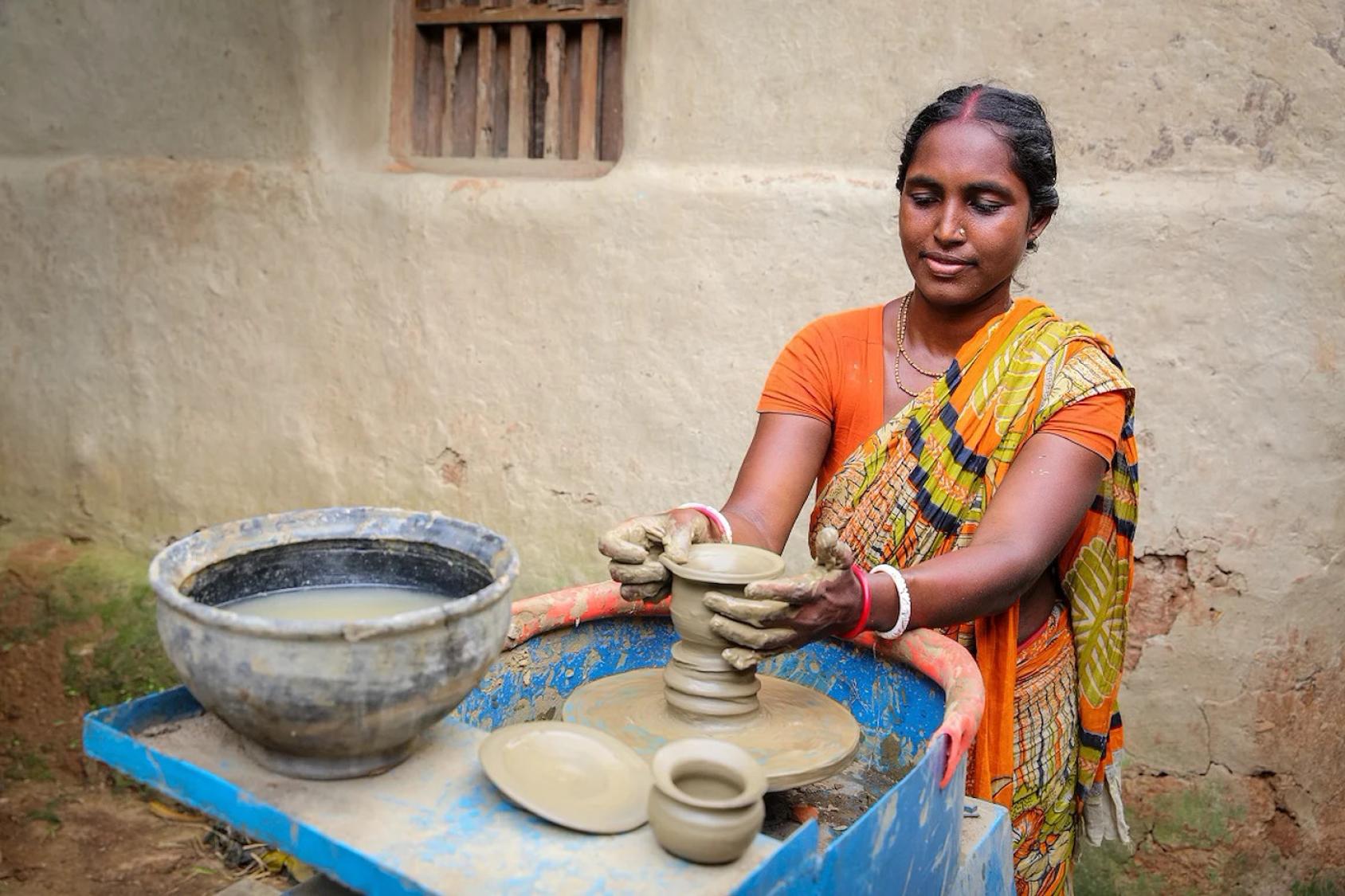 A woman in Bangladesh makes a pot out of clay.