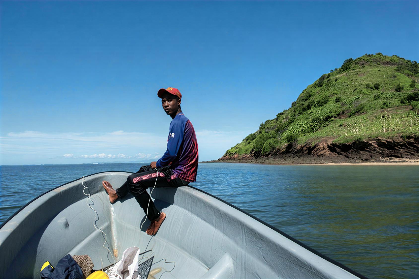 A young man in Comoros sits on a boat.