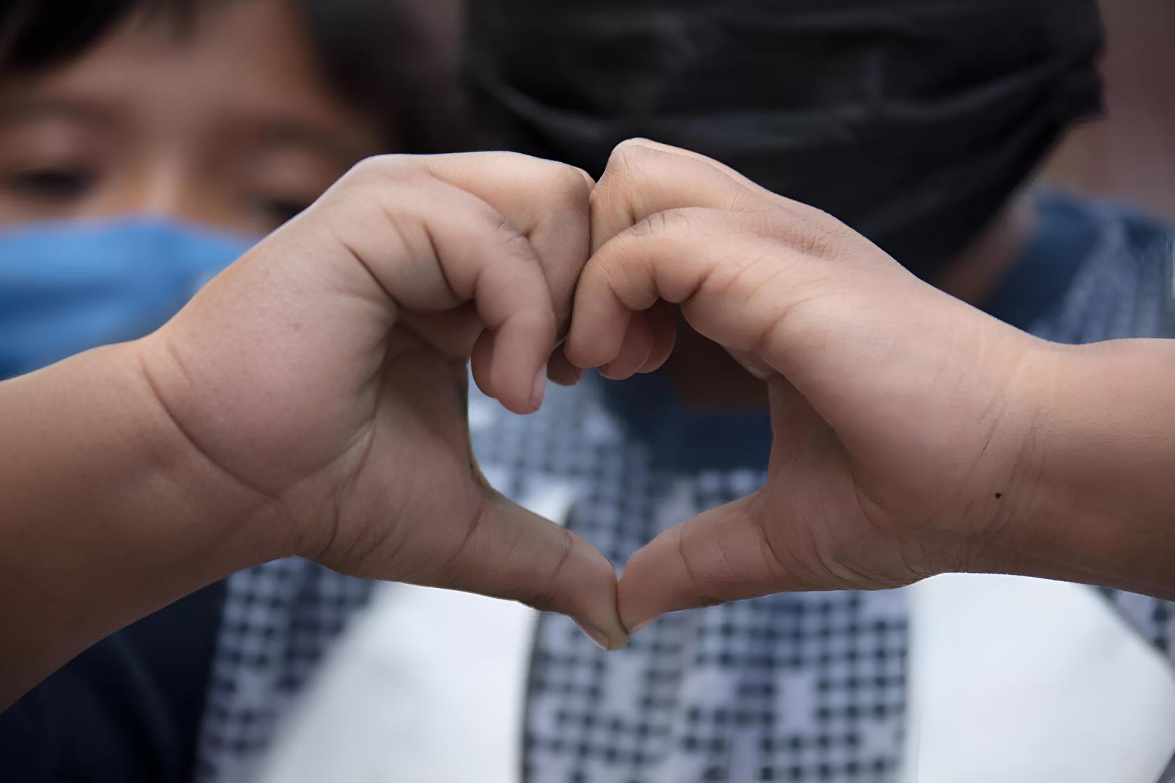 A child makes a heart shape with her hands.