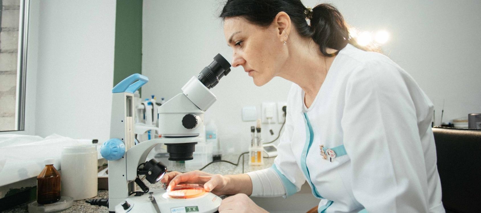 A doctor in Ukraine looks through a microscope.