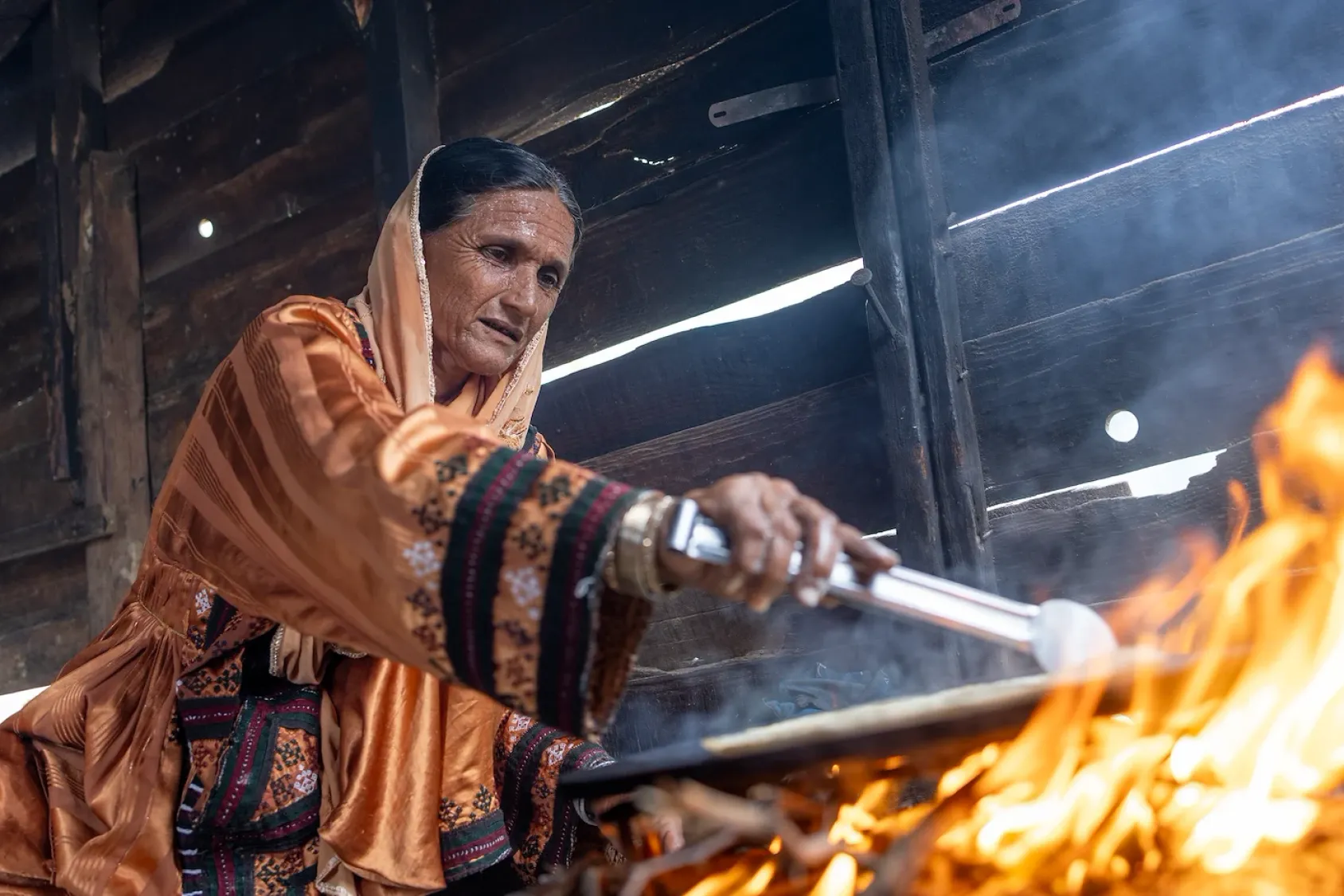 Une femme prépare un repas sur un feu traditionnel, illustrant les défis persistants liés à l’accès à une énergie domestique propre et sûre.