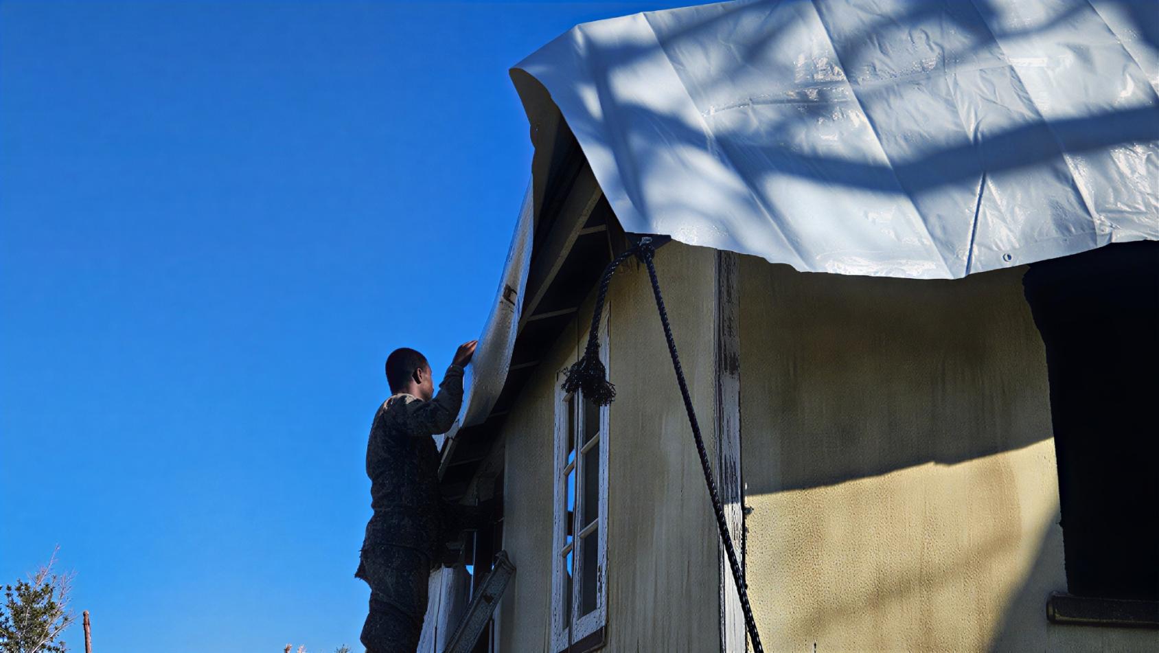 A solider in Jamaica installs a tarpaulin.