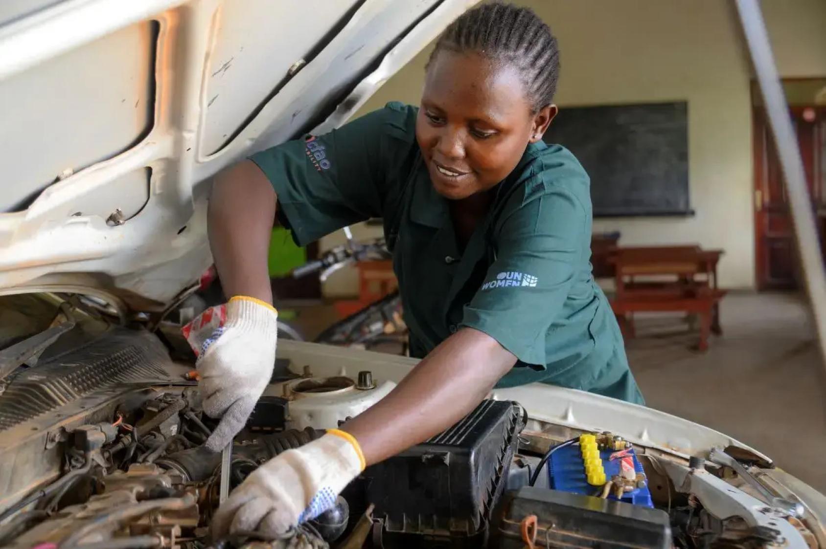 A woman mechanic works on a car engine.