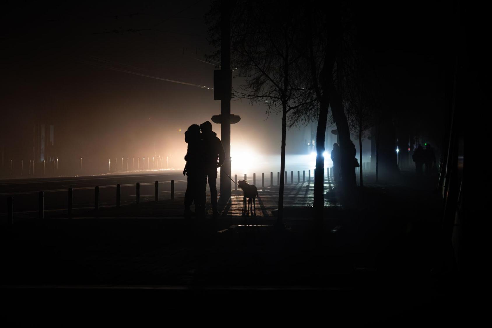 A couple in Ukraine walks their dog during a blackout.