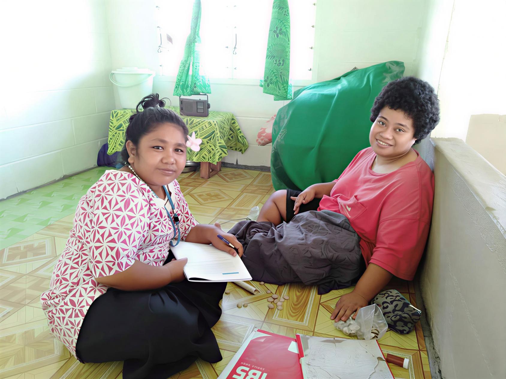 Two women with disabilities sit together in Samoa.